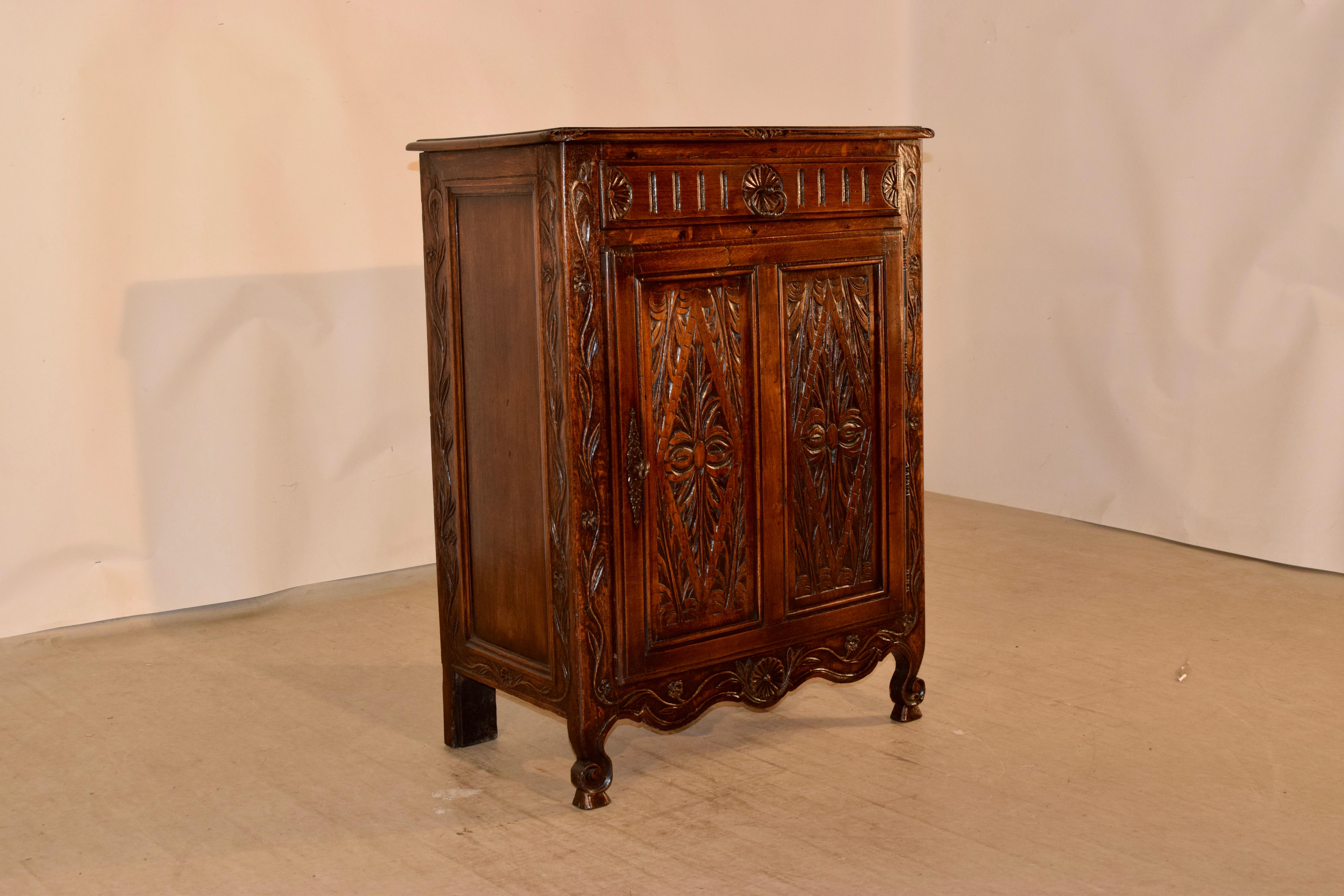 19th century oak buffet from France with a beveled edge around the top with nice hand carved details on the corners and front, following down to raised paneled sides which have carved borders. The front is spectacularly hand carved, and has a single