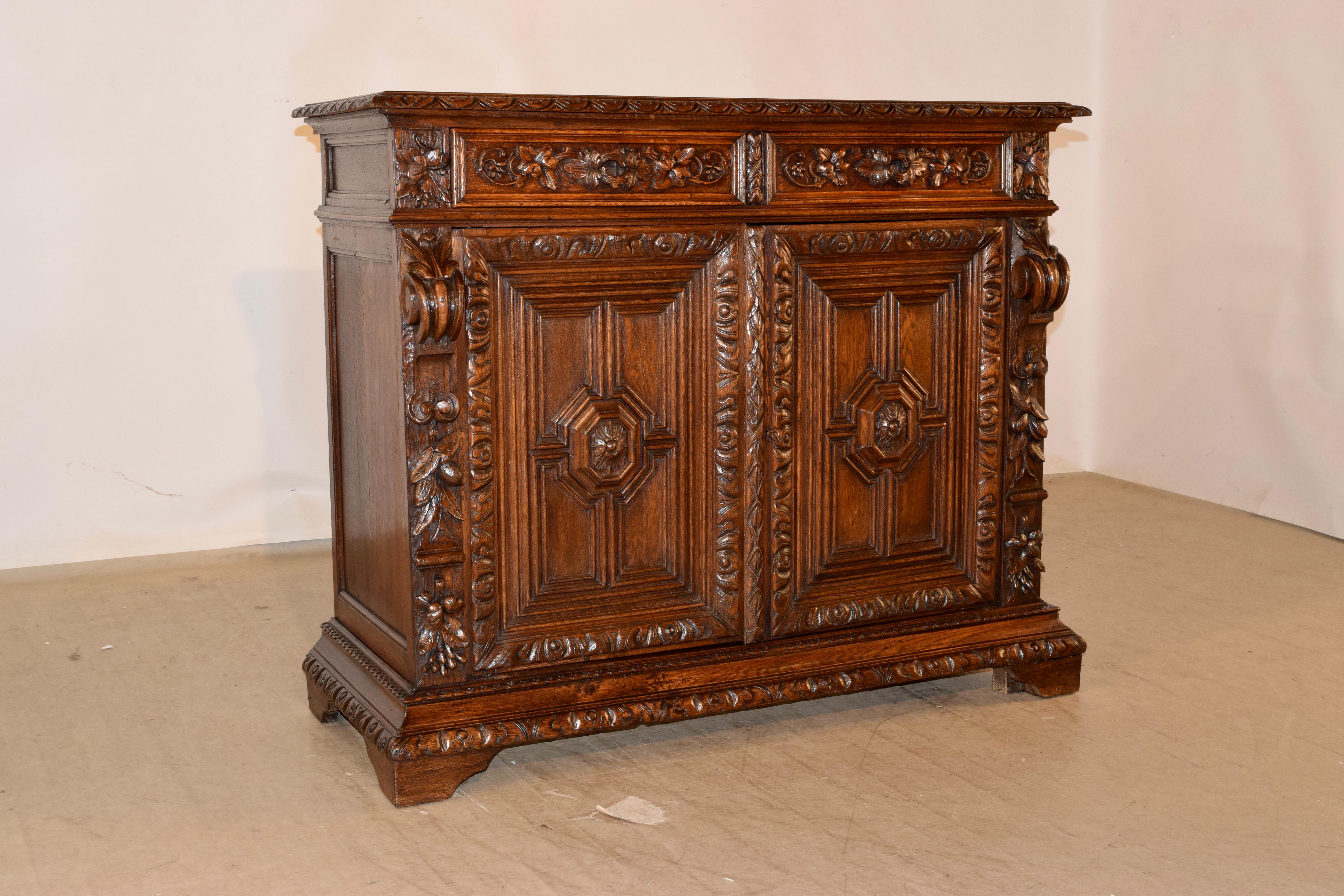 Buffet in quercia del XIX secolo proveniente dalla Francia con un bordo decorato a lunetta splendidamente modellato e intagliato a mano intorno al piano, che scende fino ai deliziosi e semplici fianchi rivestiti a mano e a due cassetti sopra due