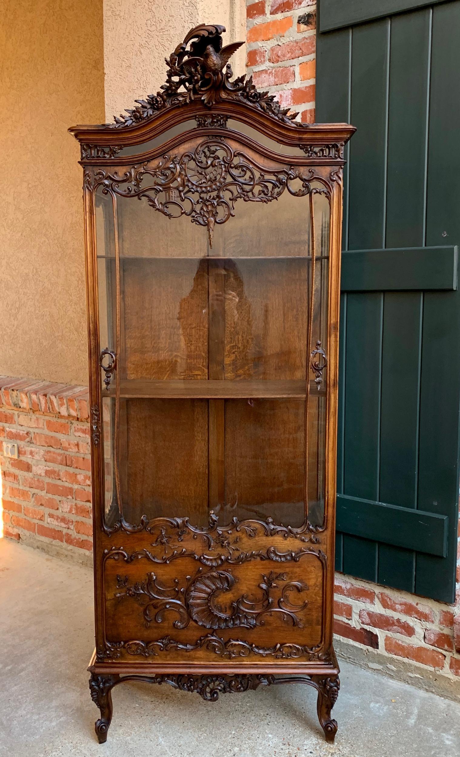 19th century French carved oak glass vitrine display cabinet bookcase Louis XV

~ Direct from France
~ Stunning antique French carved display cabinet, with superb Louis XV carved details throughout
~ Upper crown features a bird with outstretched