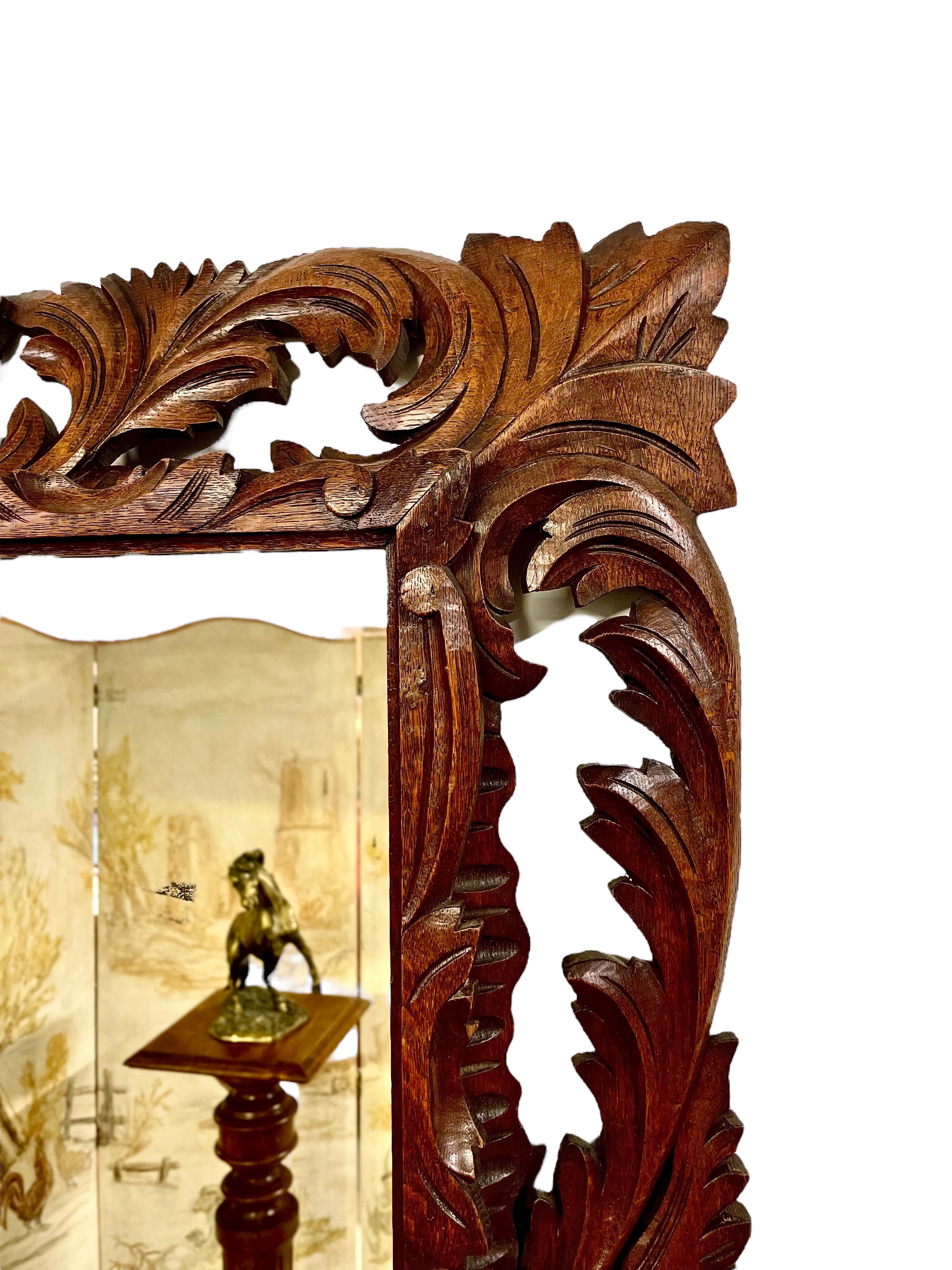 Impressive mirror made of carved and pierced oak in the Henri II style, adorned with acanthus leaf motifs. It dates back to the 19th century and has a charming presence of 'foxing' on the glass surface. This mirror is a fine example of craftsmanship