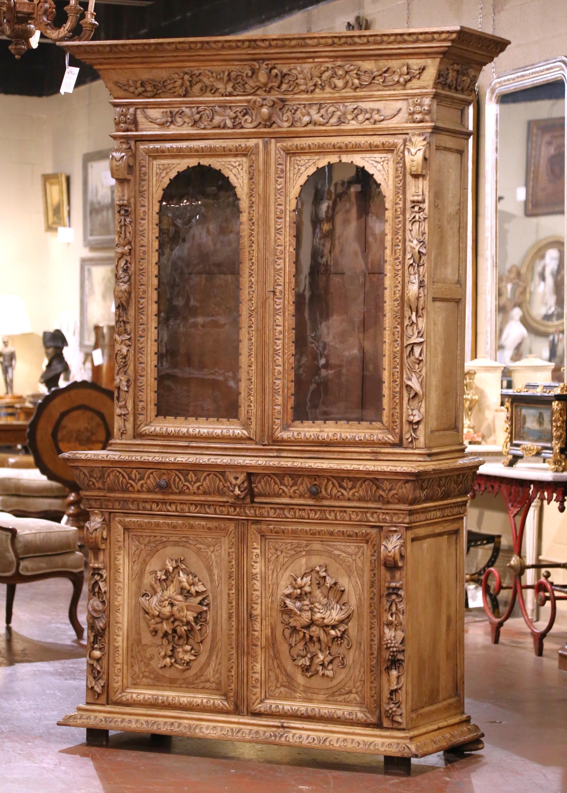 Display your rifle or shotgun collection in this grand and intricately carved antique gun cabinet. Created in France circa 1860, this important two-piece display piece is crafted from solid oak and features a light bleached finish that enhances the
