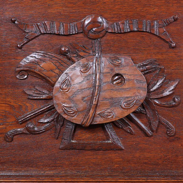 A 19th century French highly-carved oak Renaissance-revival two door bookcase, the paneled doors featuring carved scholarly and artistic motifs, the single lower drawer with a carved mythical creature ‘handle’. Boldly-molded crown and turned barley