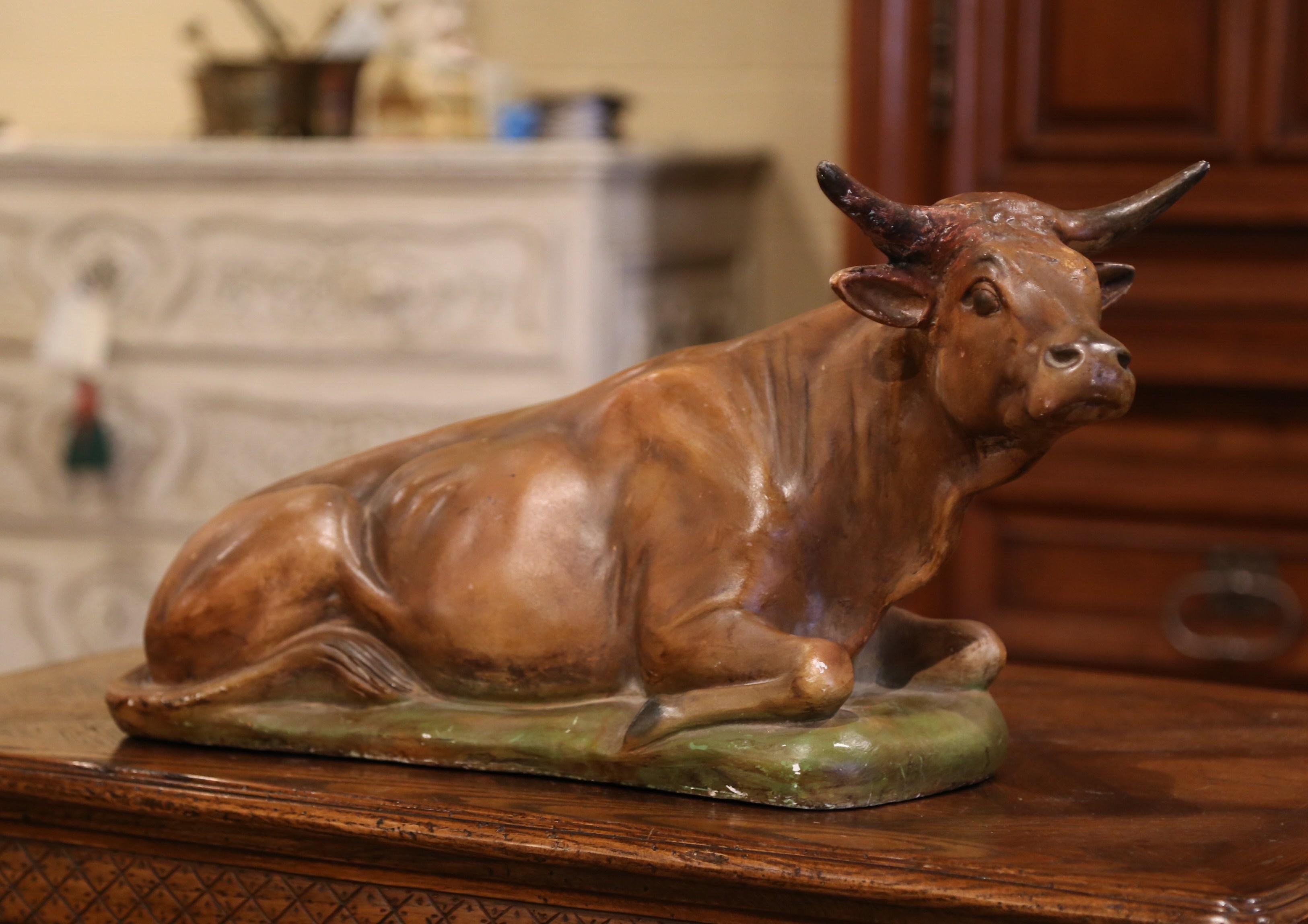 This antique bovine sculpture was crafted in Normandy, France, circa 1890; made of terracotta, the carved sculpture features a cow and in a resting position on a rectangular base. The large sculpture is in excellent condition with a rich patinated