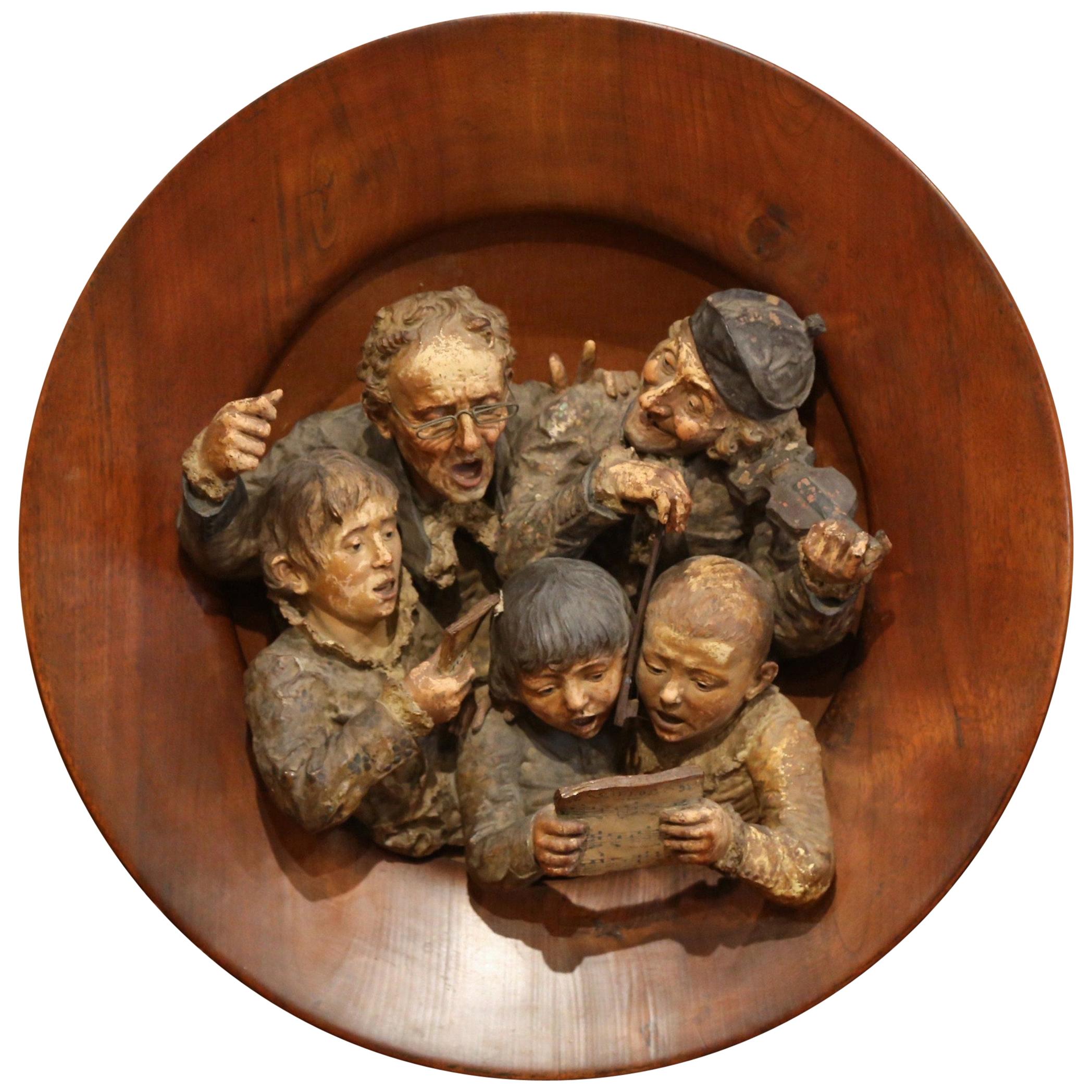 Decorate a wall in a study or game room with this exquisite terracotta wall composition. Crafted in France circa 1880, the large sculpture sits inside a large round wooden frame, it features a choir of five people carved in high relief (three