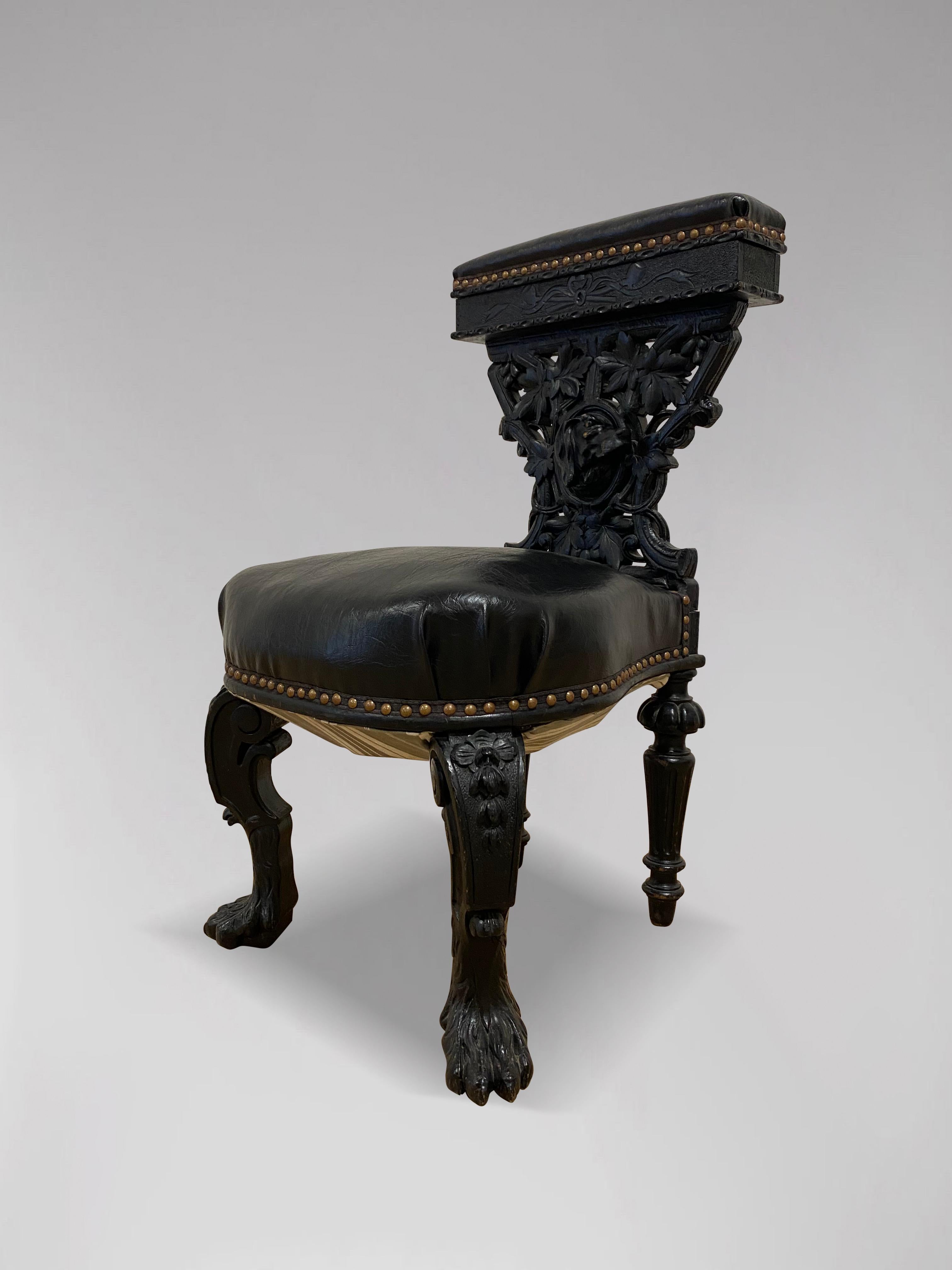 A 19th century French elaborately hand carved ebony cross splat Prie-Dieu or prayer chair. A religious kneeler from the late 19th century, featuring a padded black leather top rail and seat, accented by nailhead tack trim. The exceptionally executed