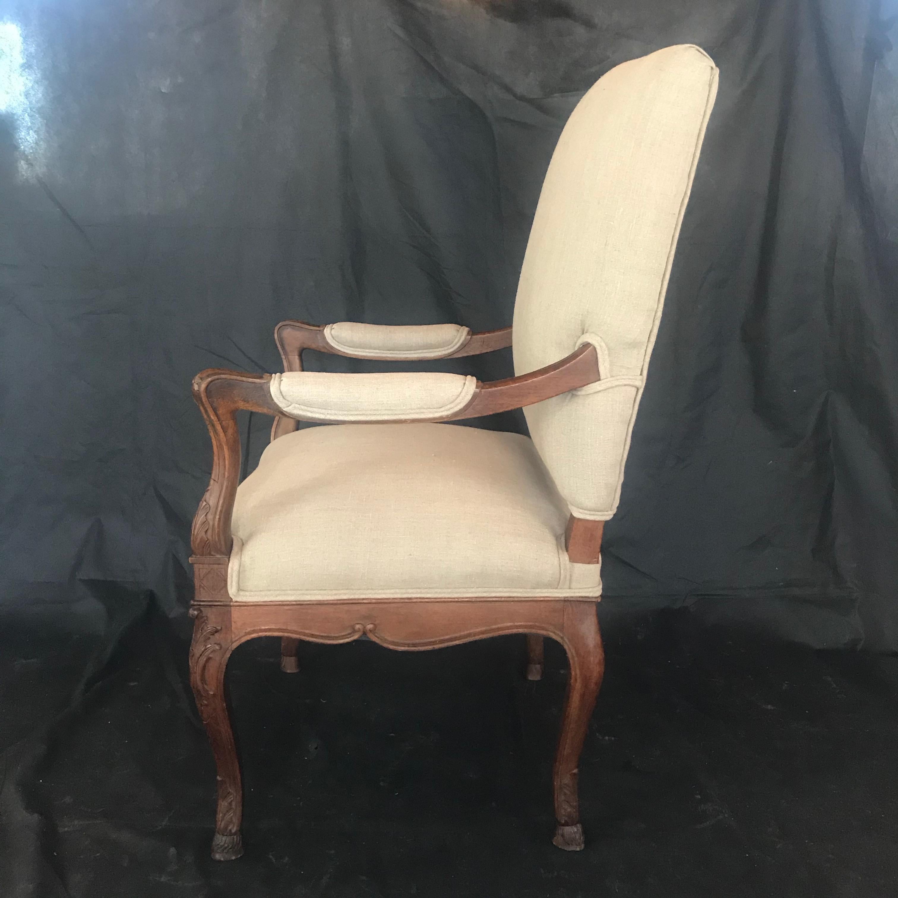 A lovely Louis XV chair with a framed back adorned with frieze and carved scroll with rosette on the center front apron. This beautiful large French solid walnut elbow chair has shaped and scrolled arms, a carved frieze and stands on carved cabriole