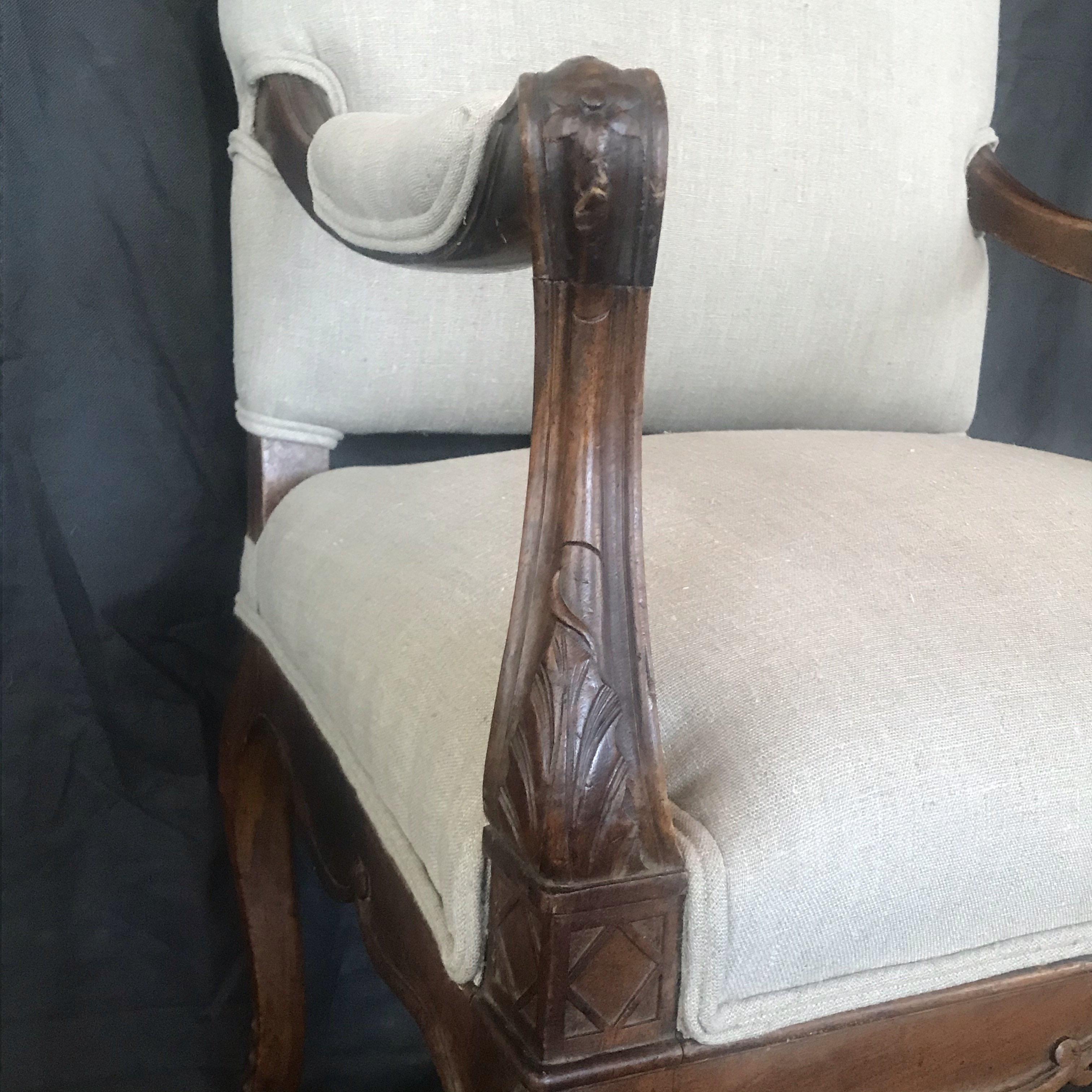A lovely Louis XV chair with a framed back adorned with frieze and carved scroll having rosette on the center front apron. This beautiful large French solid walnut elbow chair has shaped and scrolled arms, a carved frieze and stands on carved