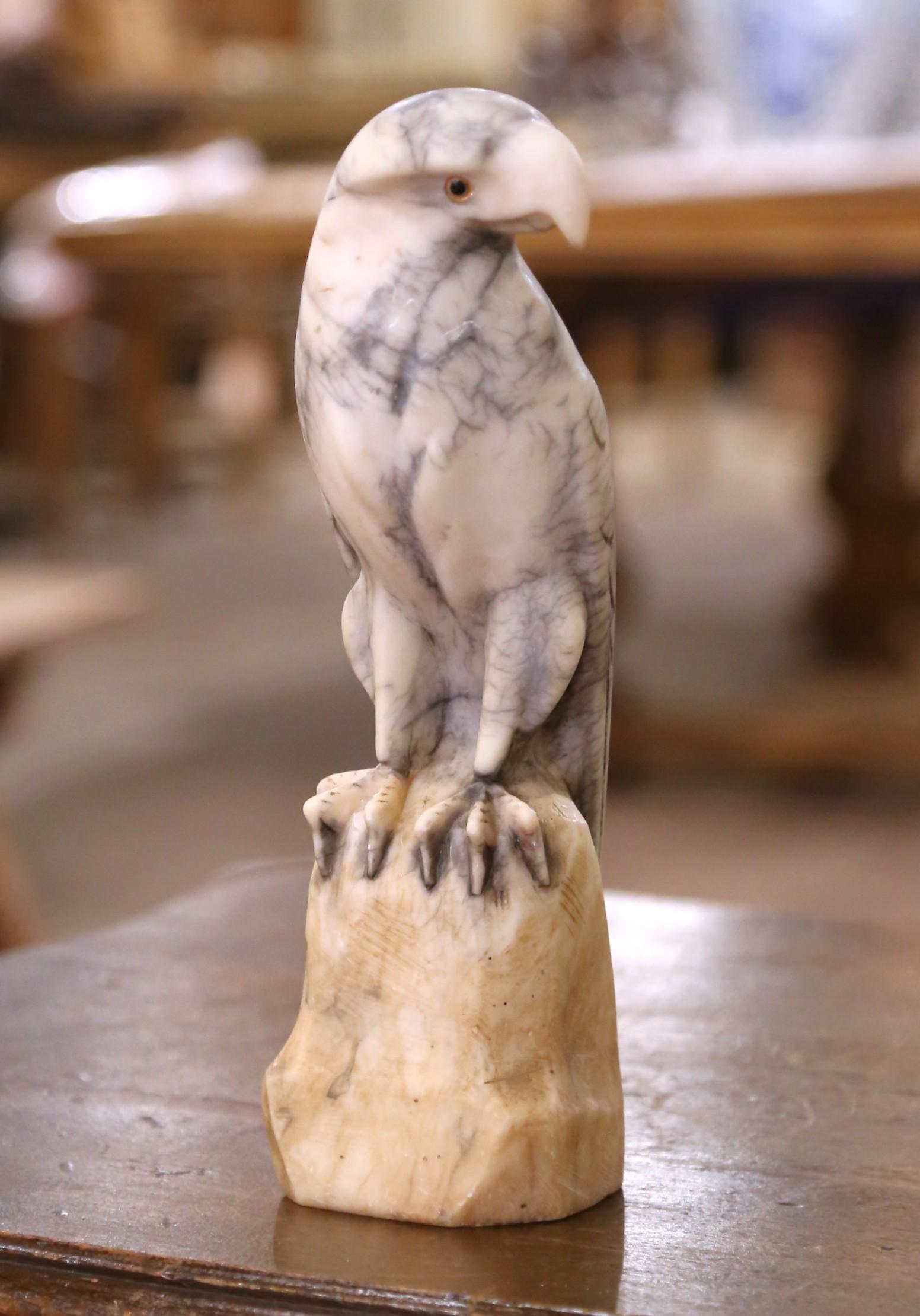 Carved in France circa 1880, this striking eagle sculpture captures the commanding presence of a bird of prey in exquisite detail. Sculpted from a single piece of variegated marble, the figure rests atop a naturalistic rocky base and features subtle
