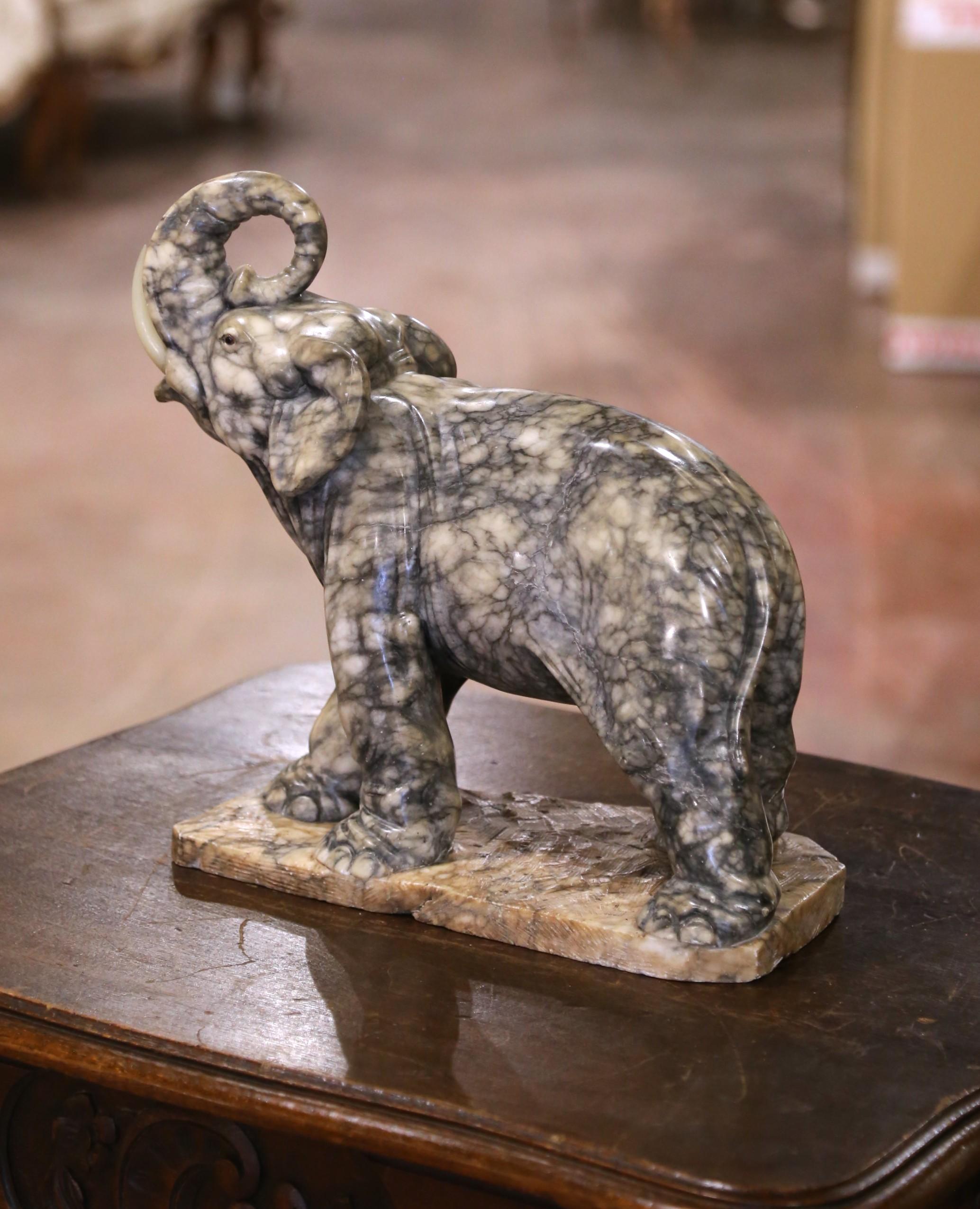 Carved in France in the late 19th century, this substantial elephant sculpture is crafted from richly variegated marble and weighs approximately 27 pounds. Captured mid-stride with its trunk raised, a traditional symbol of good fortune and