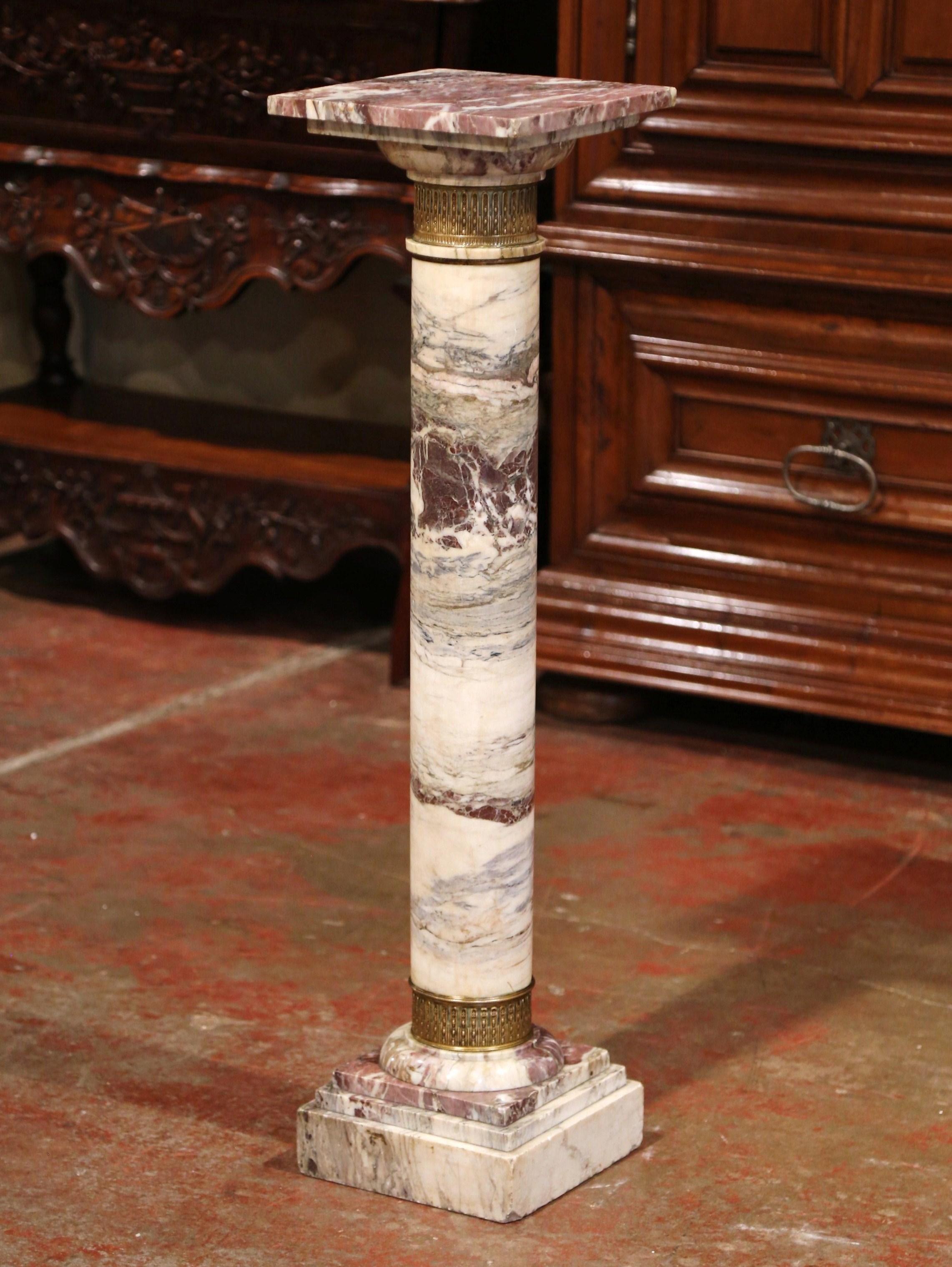 This elegant, antique multi-color marble pedestal table was crafted in France, circa 1870. The Napoleon III pedestal sits on a sturdy square plinth base embellished with an engraved floral motif brass mount at the bottom. The round stem is decorated