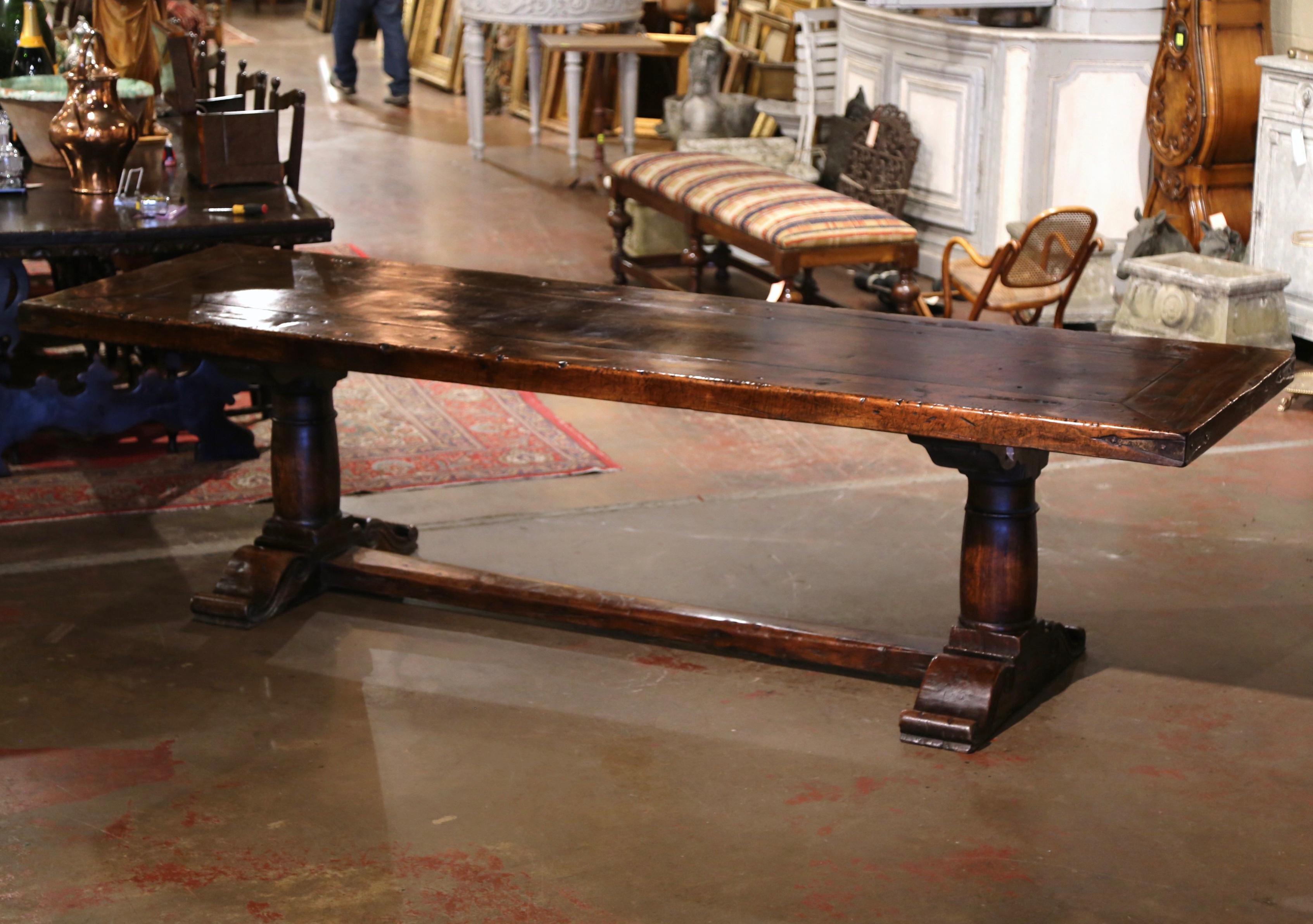 This large antique dining room table was crafted in southwest France, near the Spanish and French border circa 1880. Built with walnut and chestnut timber, the 9 foot table stands on hand carved baluster legs ending with shoe base, and connected