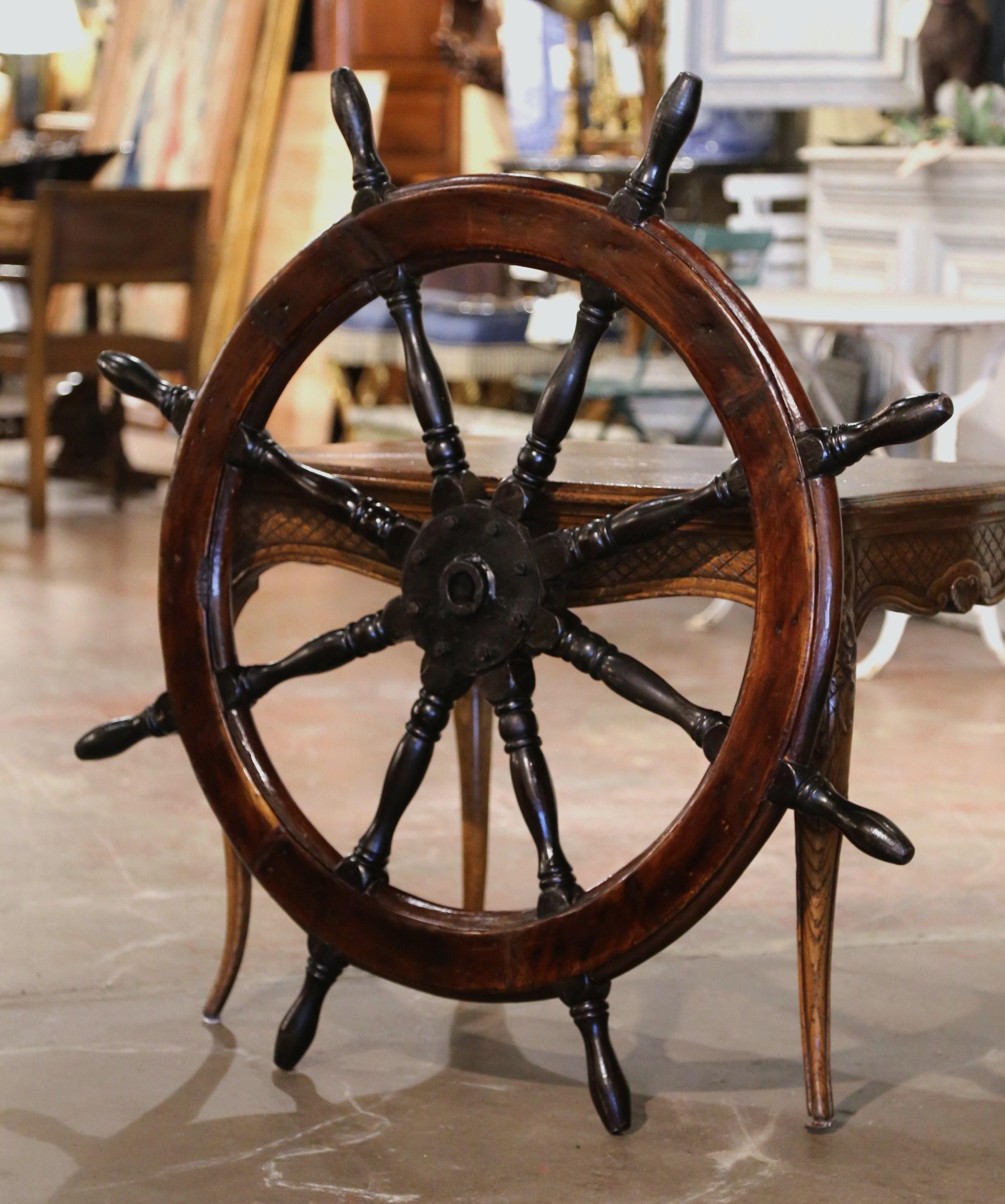 This antique wooden ship wheel was carved in France, circa 1880. The traditional, fruit wood nautical object has its original metal brace, eight turned handles and is in excellent condition commensurate with age and use, and adorns the original rich