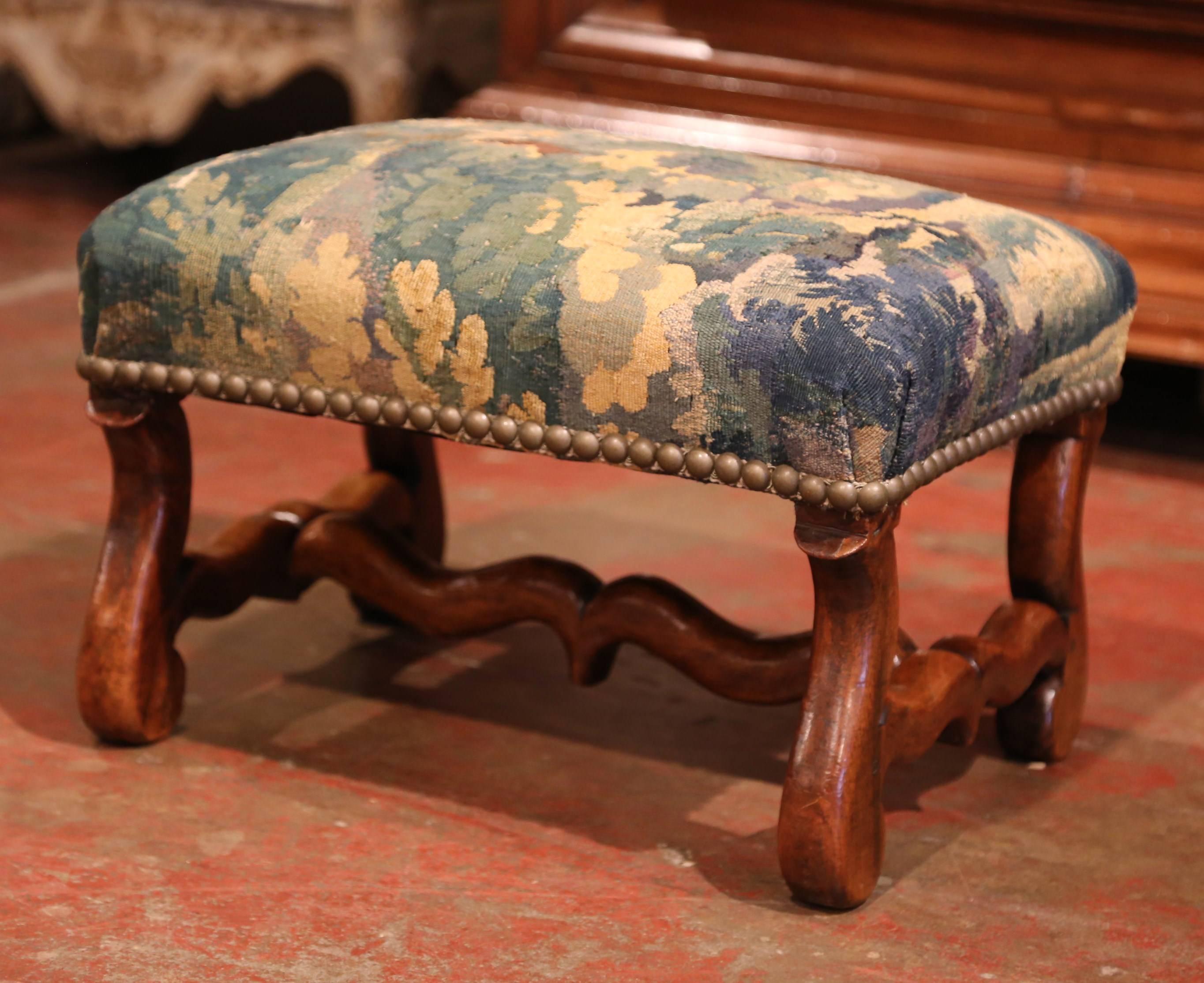 This elegant, antique footstool was crafted in Lyon, France, circa 1860. The large carved, rectangular footrest has been reupholstered with old Aubusson verdure fragment; the stool is further embellished with decorative nail heads and the tapestry