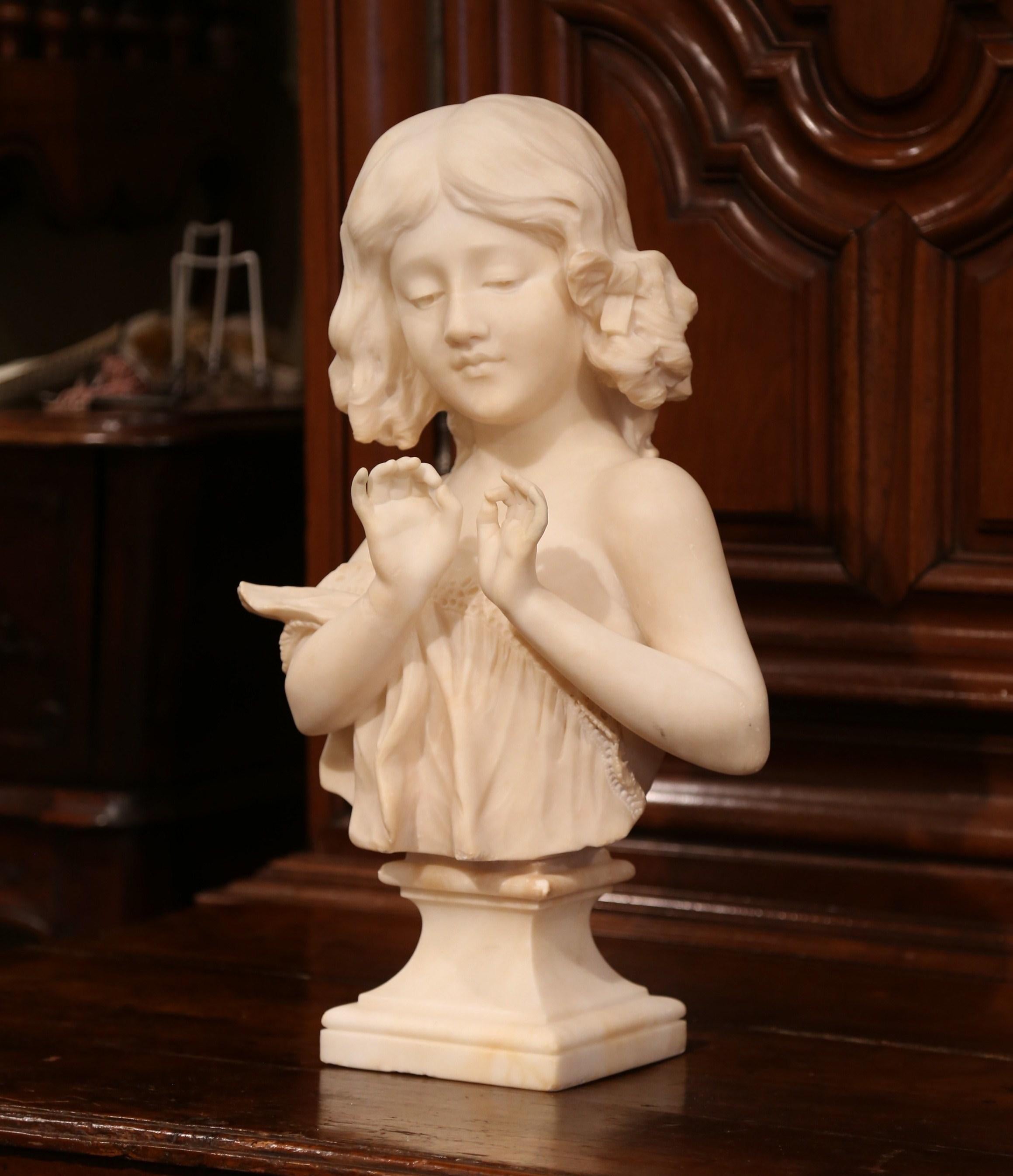 Crafted in France circa 1890, this two-piece white marble bust is a true representation of French elegance. The figural sculpture features the visage of a beautiful, young girl in a lace dress with delicately posed hands. There are a number of