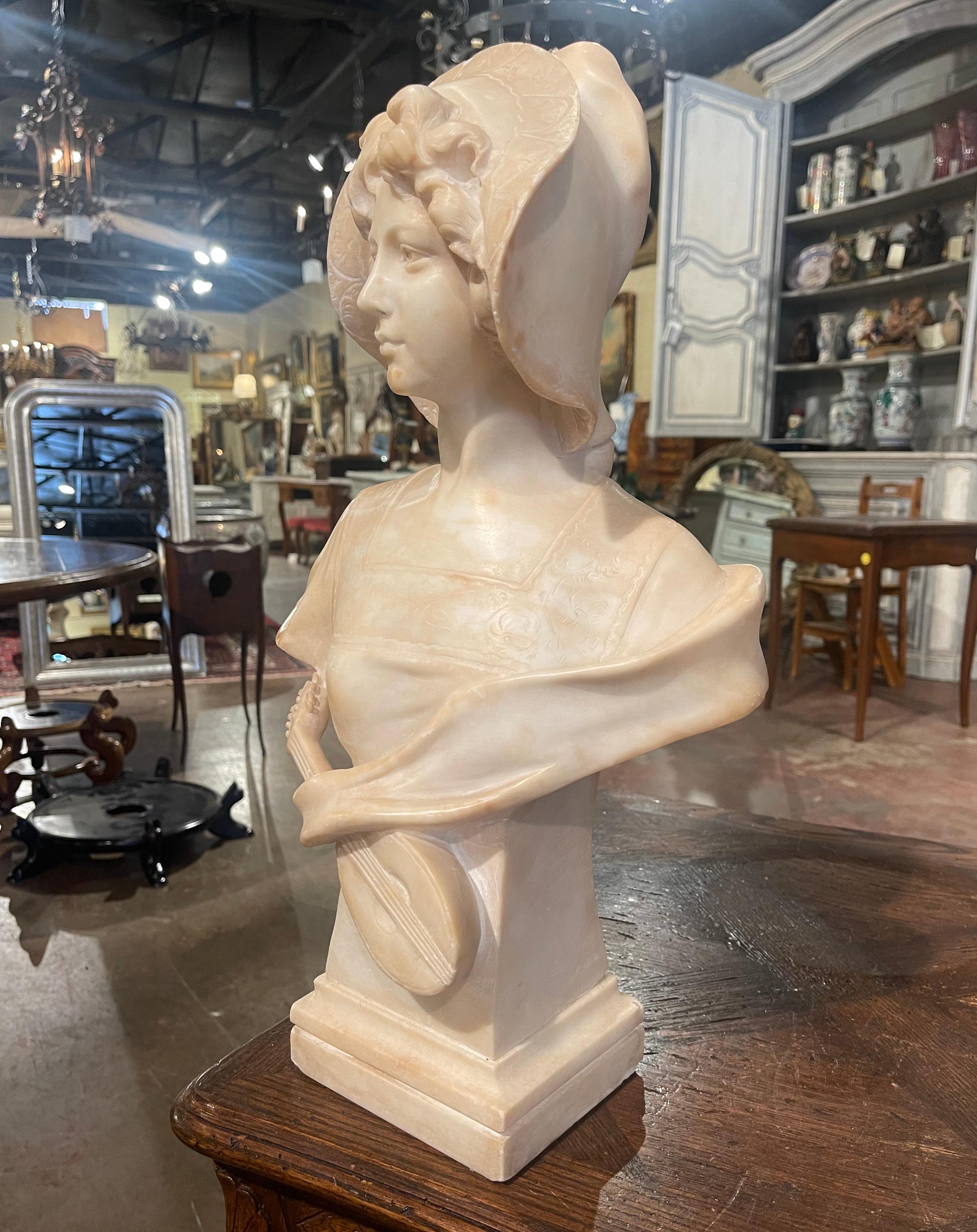 Crafted in France circa 1890, this antique marble sculpture stands on a square base, and depicts a young girl with a guitar draped in front of her. The bust, is signed on the back by the artist, and cannot be easily read. The work of art features a