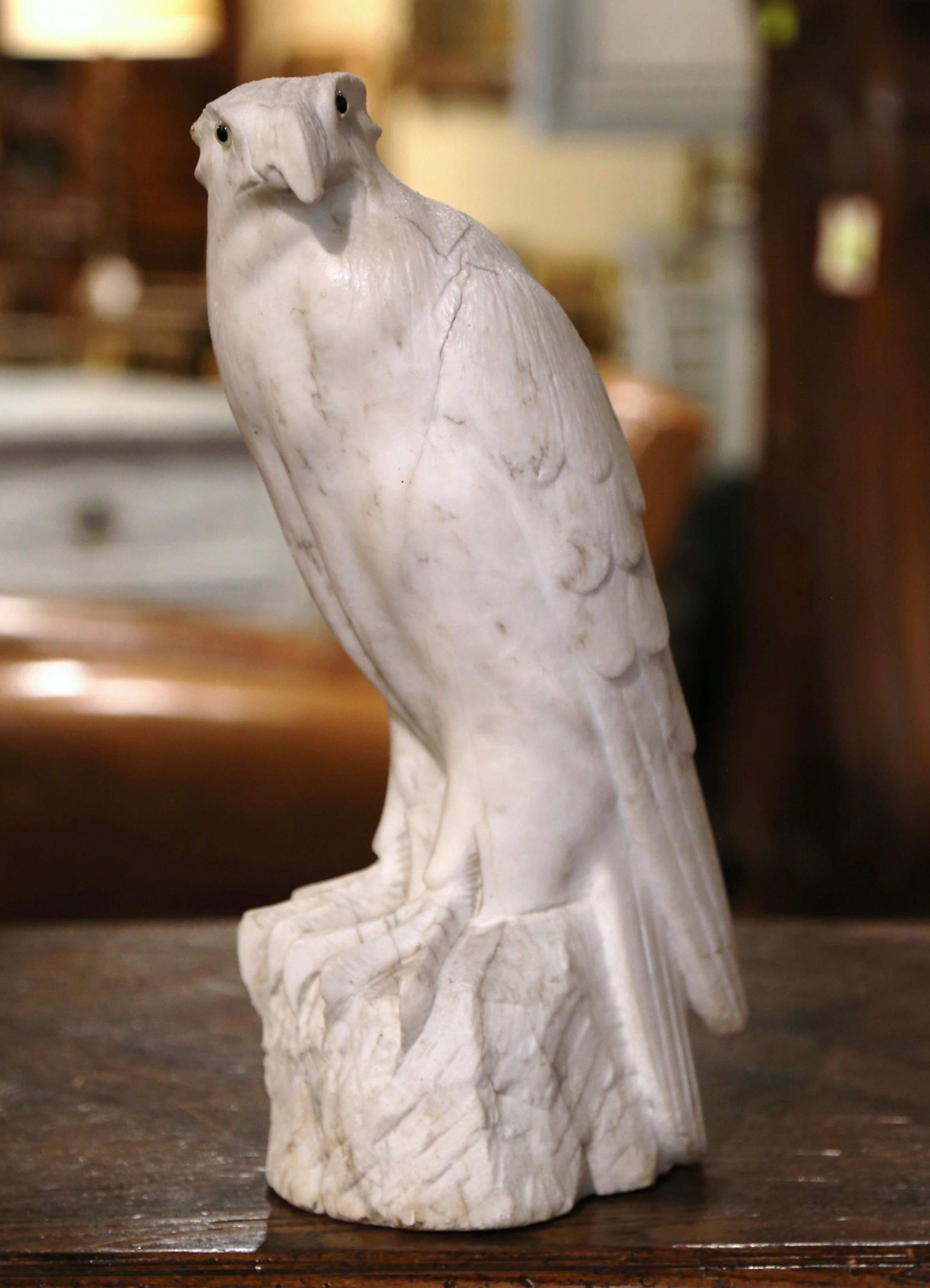 Decorate a shelf or a man's office desk with this stately carved, antique marble eagle. Created in France, circa 1870 and carved of white marble with grey veins, the tall sculpture depicts a proud bird standing on a rectangular rock with his head