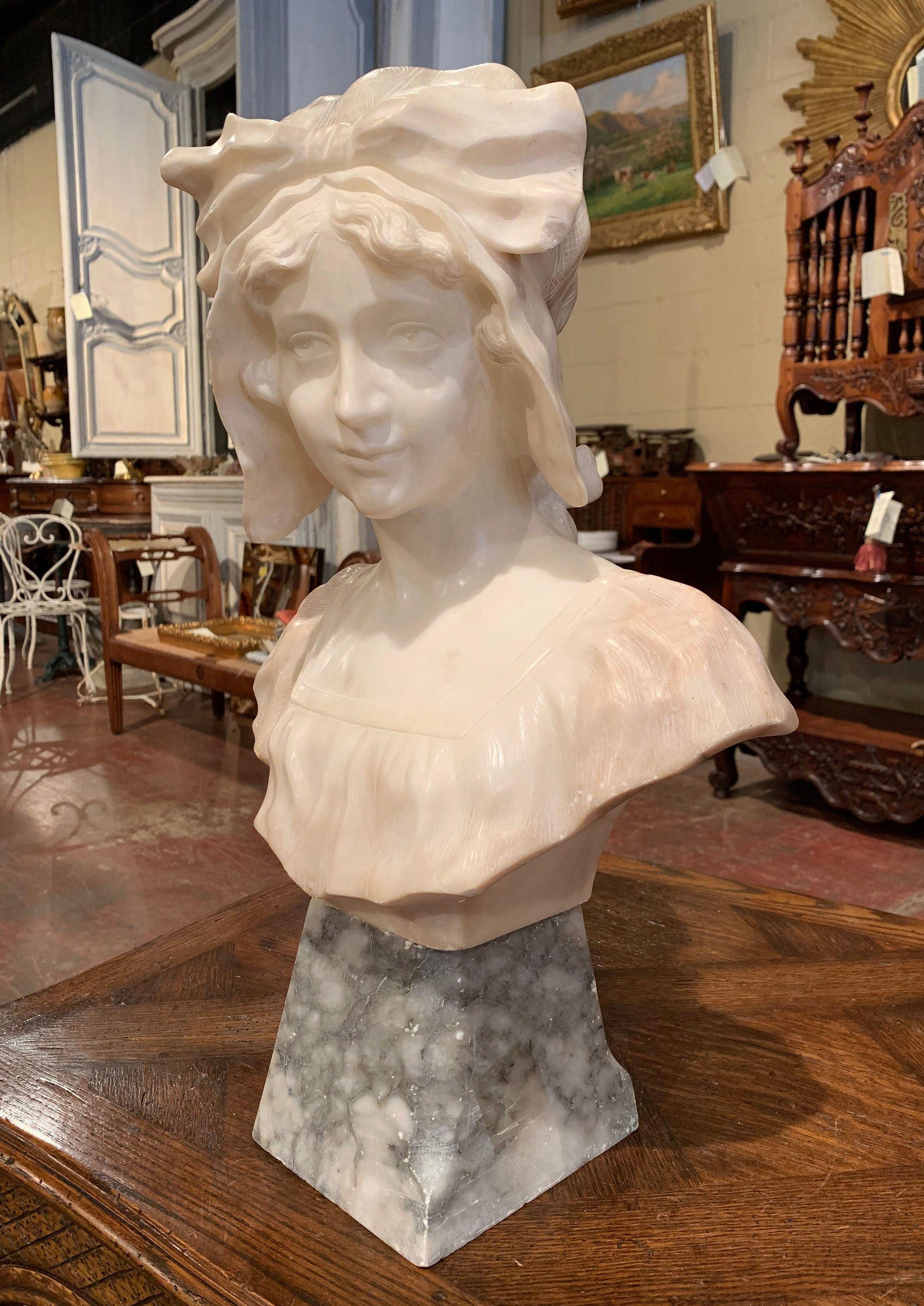 Crafted in France circa 1850, this large antique marble bust is a true representation of French elegance. Made in two sections (bust and separate base) of white and grey marble, the figural sculpture features a beautiful young beauty with hat and