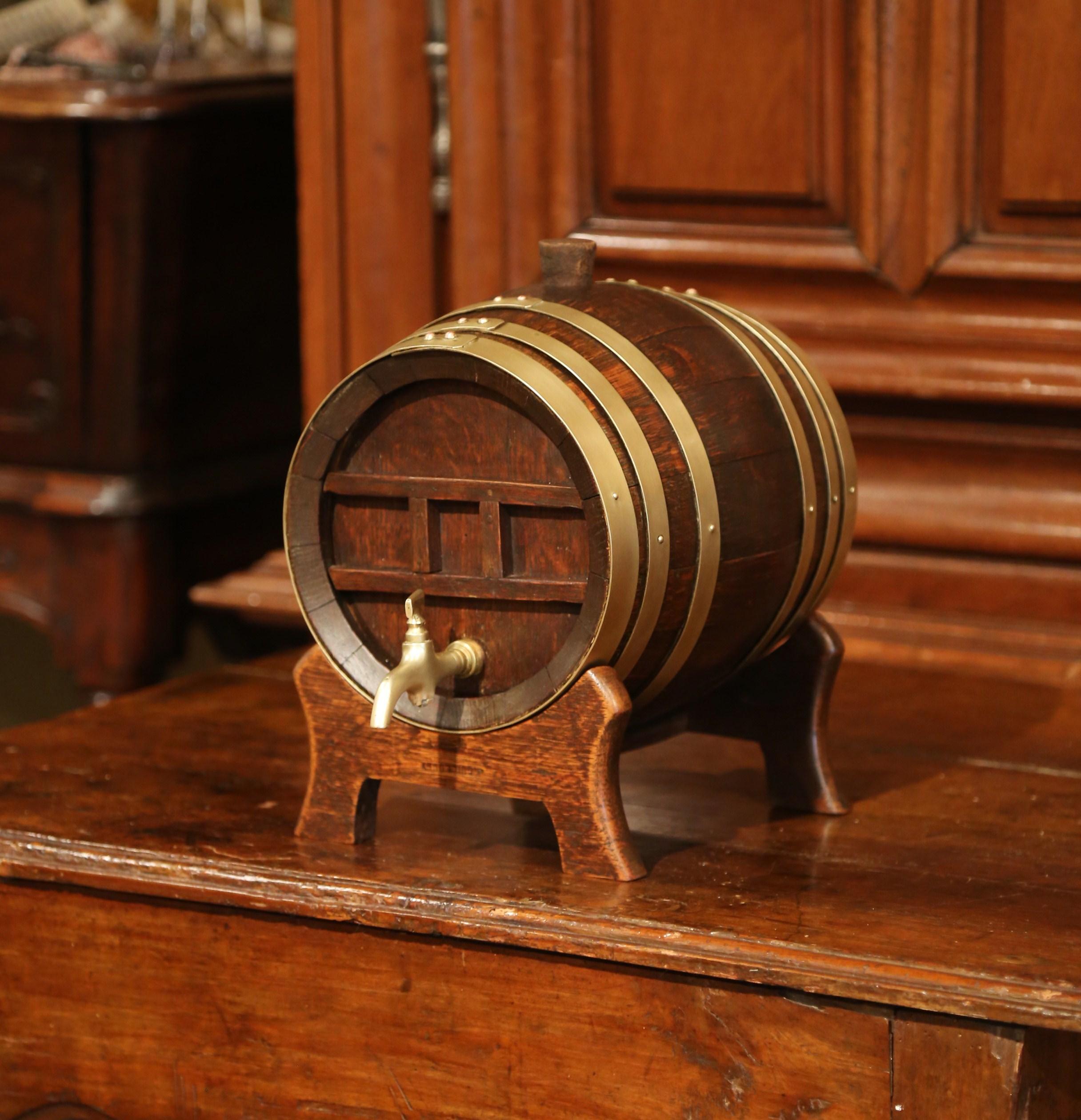 Accessorize your bar with this antique brandy barrel from Cognac; crafted circa 1880, this oval oak barrel embellished with brass rim. It sits on a separate base and features the original brass faucet and wooden cork at the pediment. The bar