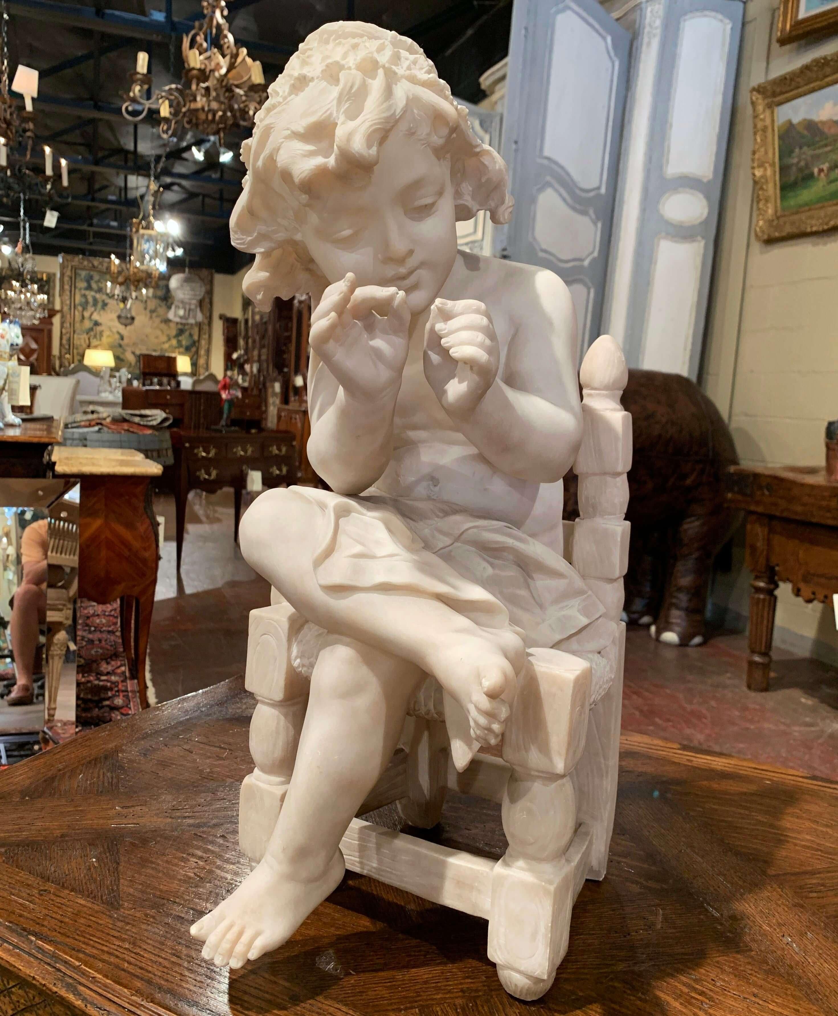 Cette composition ancienne en marbre sculpté a été fabriquée en France, vers 1870. La sculpture représente une jeune fille assise sur une chaise, les jambes croisées, jouant avec ses doigts. L'œuvre d'art présente des détails artisanaux exquis : la