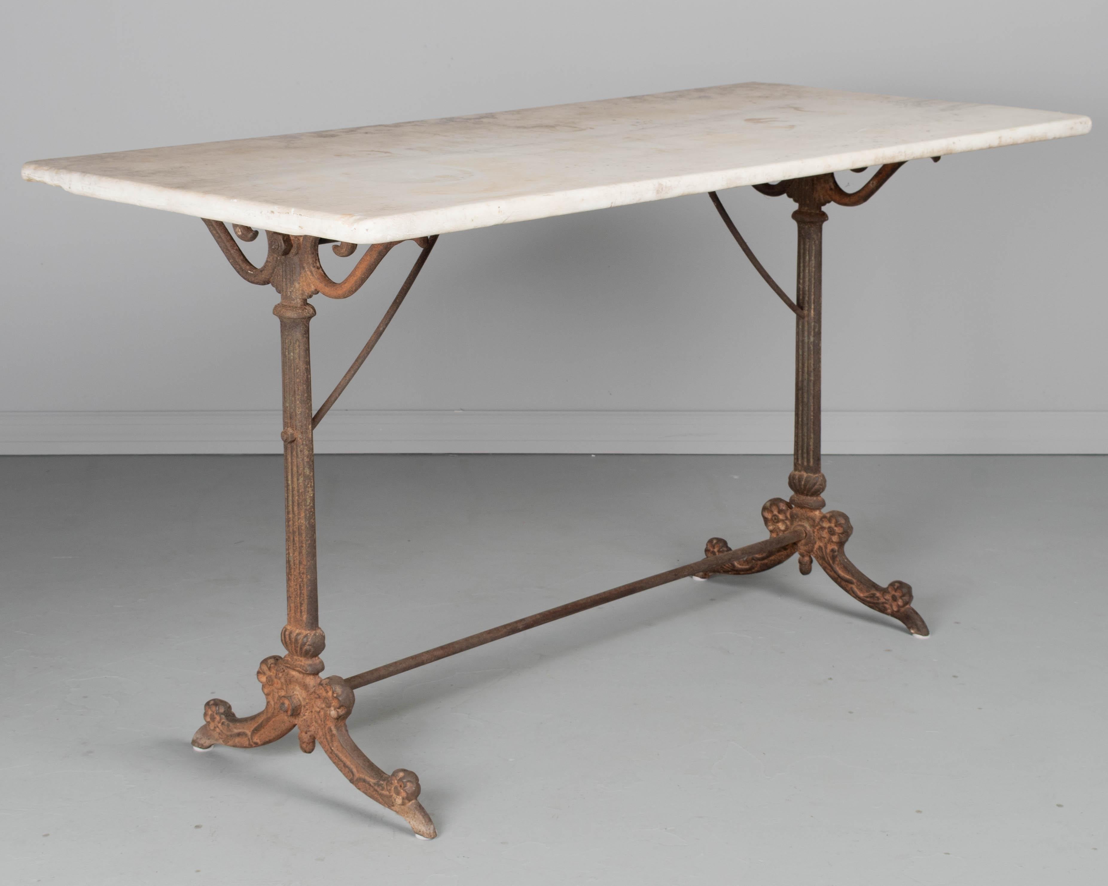 A 19th century French cast iron marble top bistro table. Large thick slab of marble with rounded corners. Good quality, heavy casting with beautiful rusty patina. Marble has worn surface and chipped corners. Great for use as an outdoor garden table.