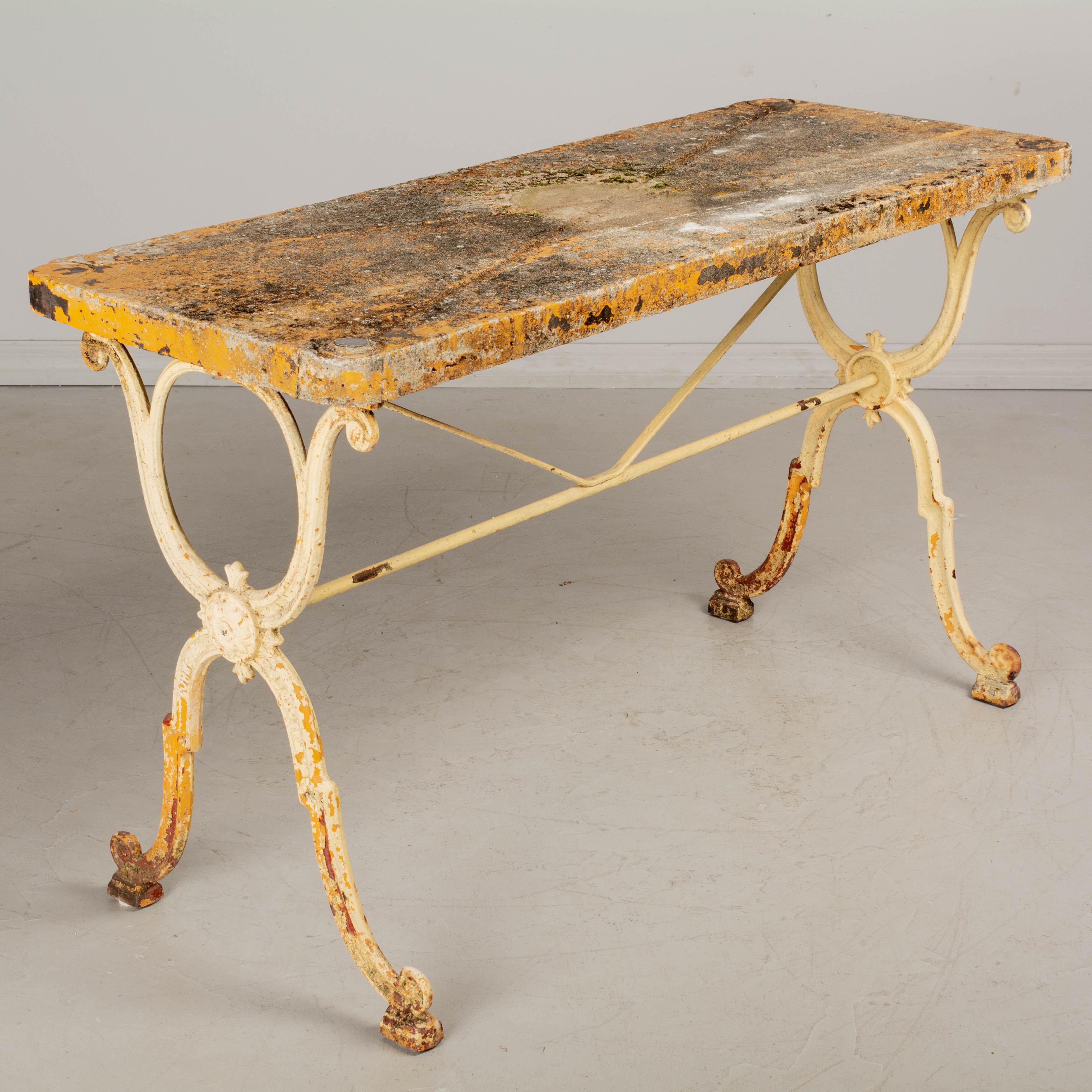 A French cast iron, marble top bistro table, or garden table, with heavy concrete top. The iron base is from the 19th century foundry Corné & Cie in Toulouse and has several layers of peeling red, yellow and white paint. Good quality, heavy casting