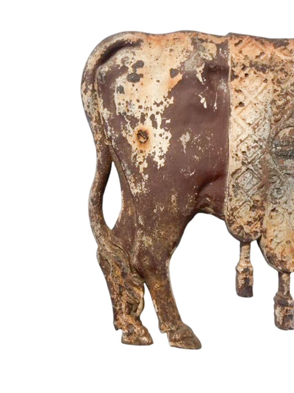 Enseigne de boucherie en fonte française conservant une peinture ancienne et moulée en bas-relief sous la forme d'un bœuf portant une couverture à glandes et ayant la tête tournée. Le moulage à blanc est orné d'un motif et d'un médaillon central