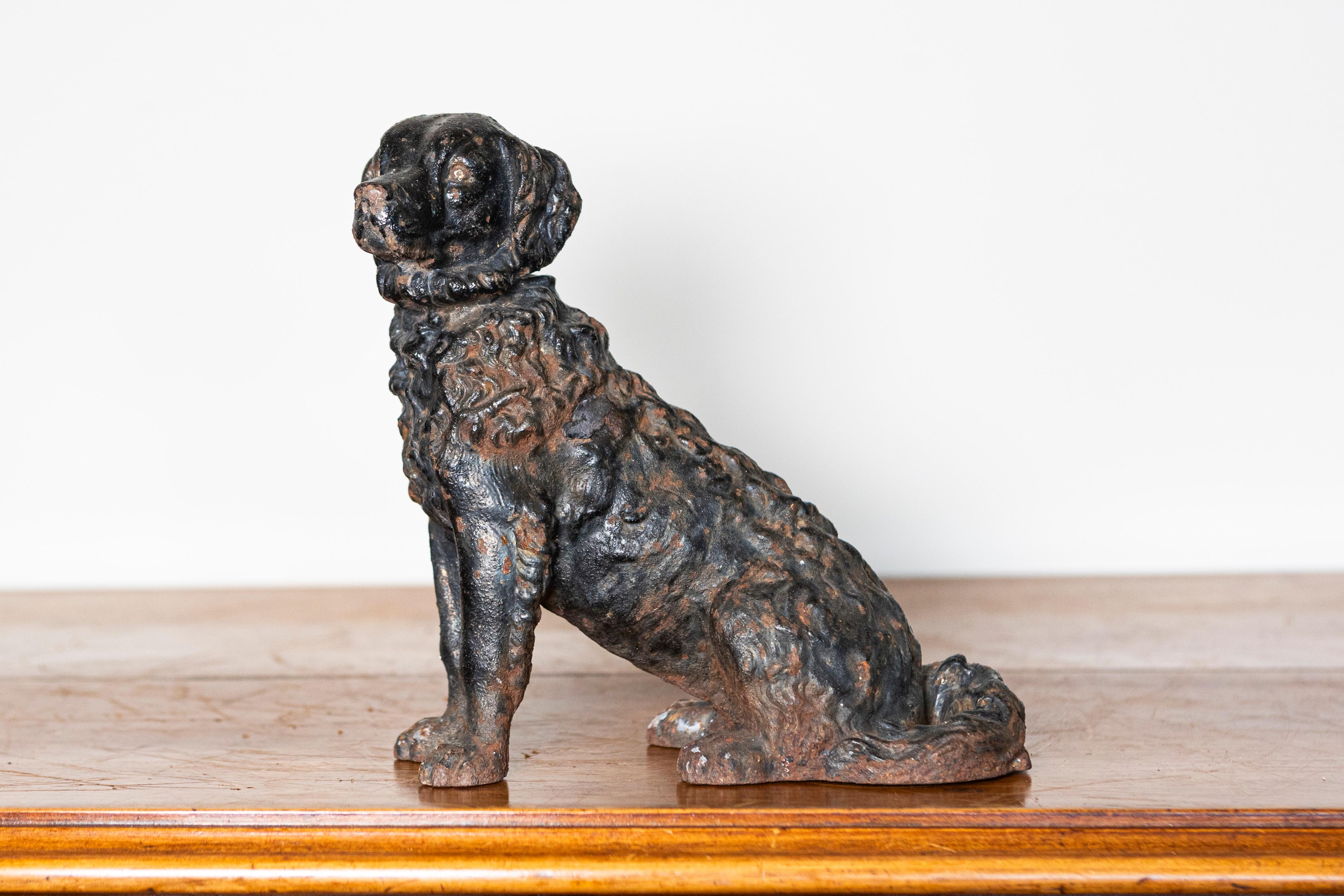 This 19th-century patinated cast iron dog sculpture is a fine example of Victorian-era craftsmanship. Depicting a seated spaniel with intricate detailing, the figure captures the lifelike texture of the fur and the regal demeanor of the breed. The