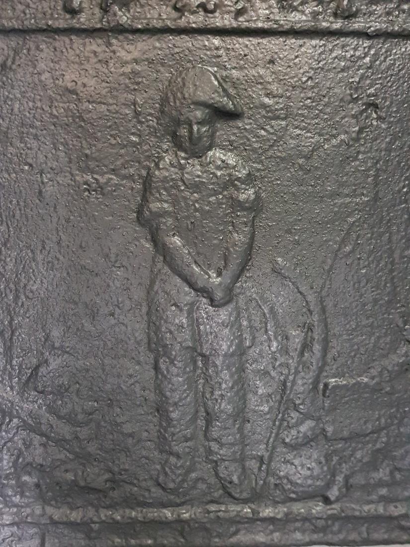 Antique French cast iron fireback with an image of a farmer with a Napoleon hat with various attributes around him, in a good but used condition. Originating from the 19th century.

The measurements are:
Depth 1 cm/ 0.3 inch.
Width 38.5 cm/ 15.1