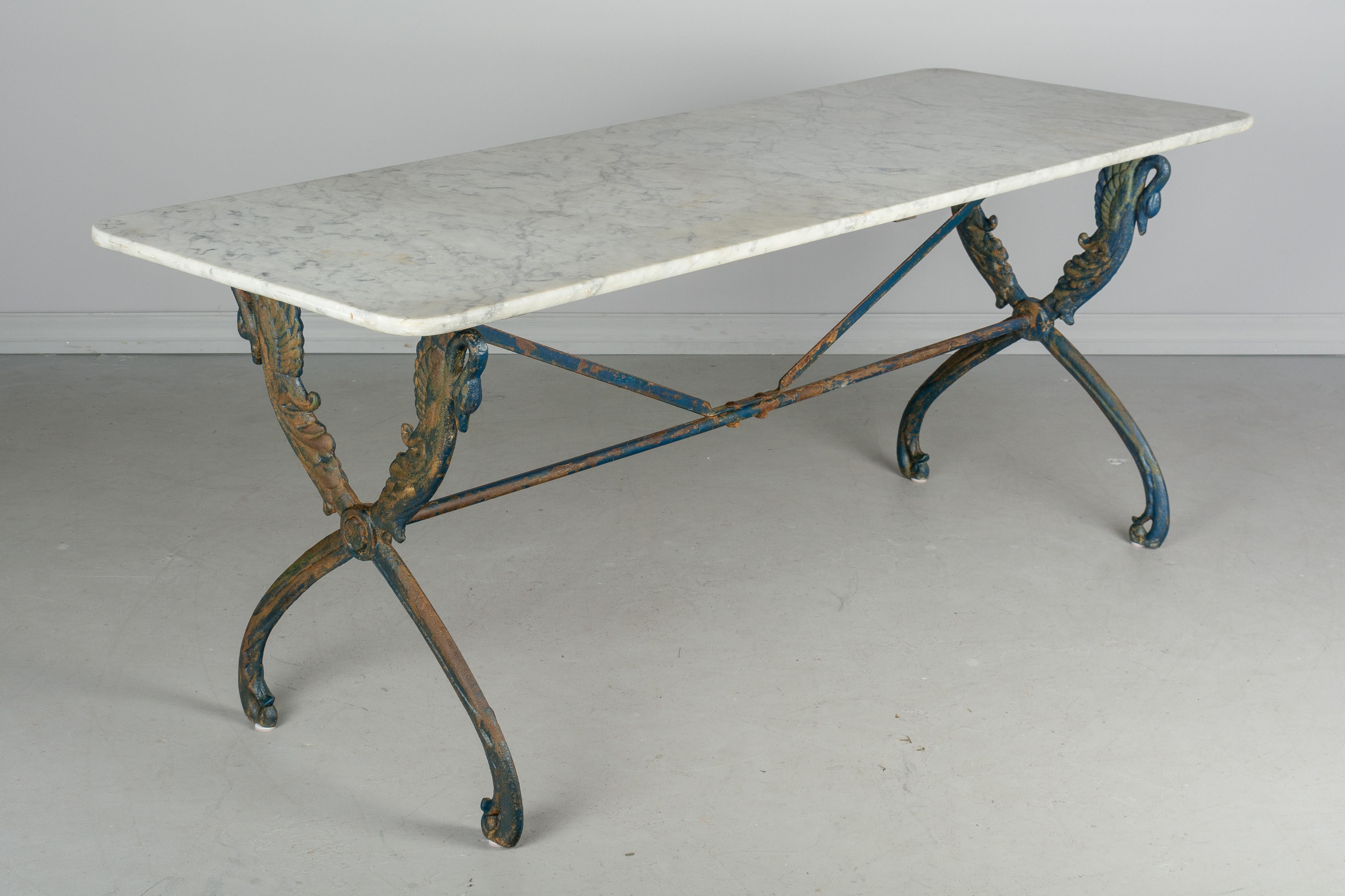 A 19th century French cast iron bistro table with marble top. Nice casting with stylized swan motif and unusual blue painted finish with old rusted patina. White veined marble top is as found.