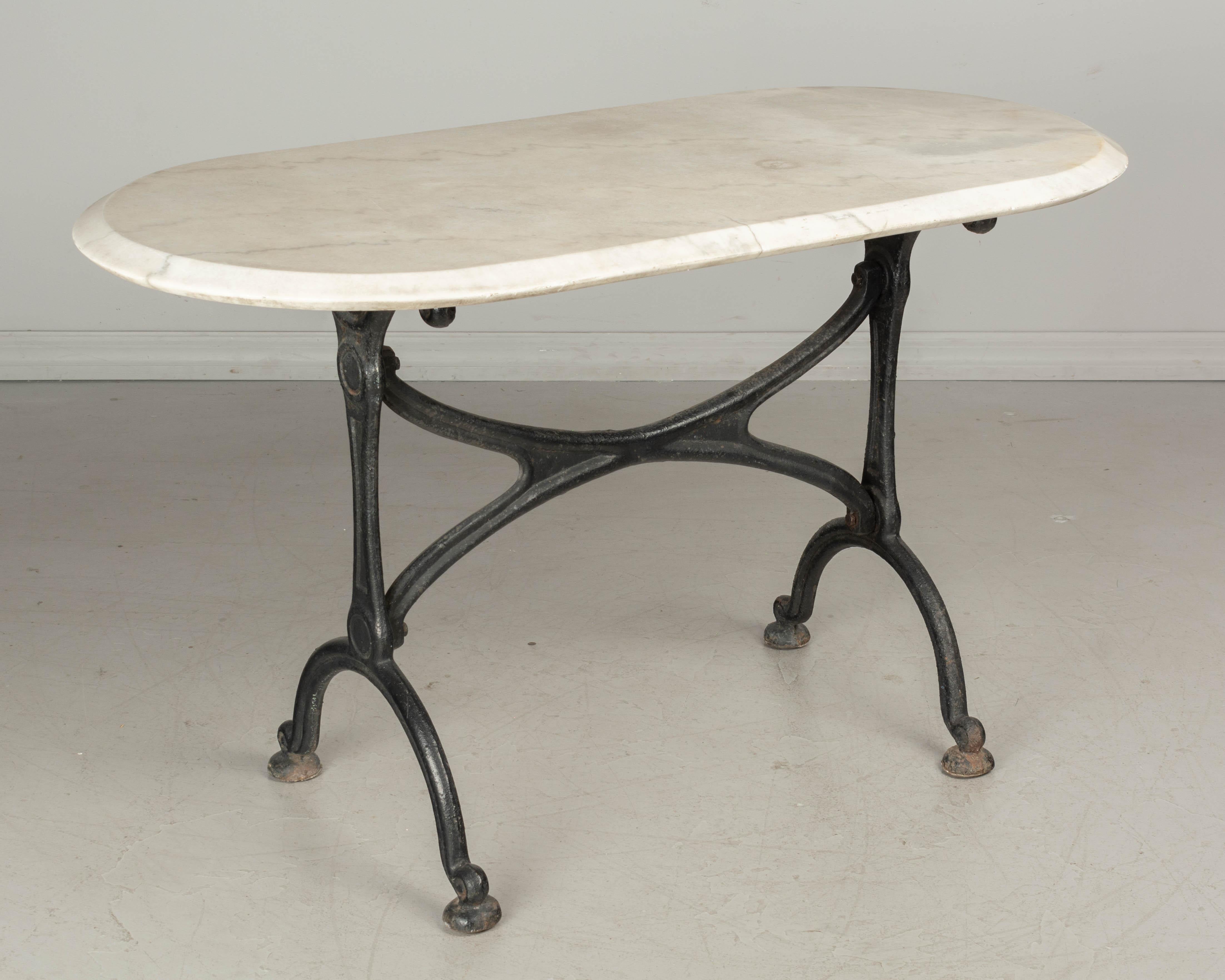 A 19th century French cast iron marble top bistro, or garden table. Heavy black painted base with good quality casting and thick stretcher. Rusty patina at the feet. Large marble top has curved corners and a deep beveled edge. Marble is from a later