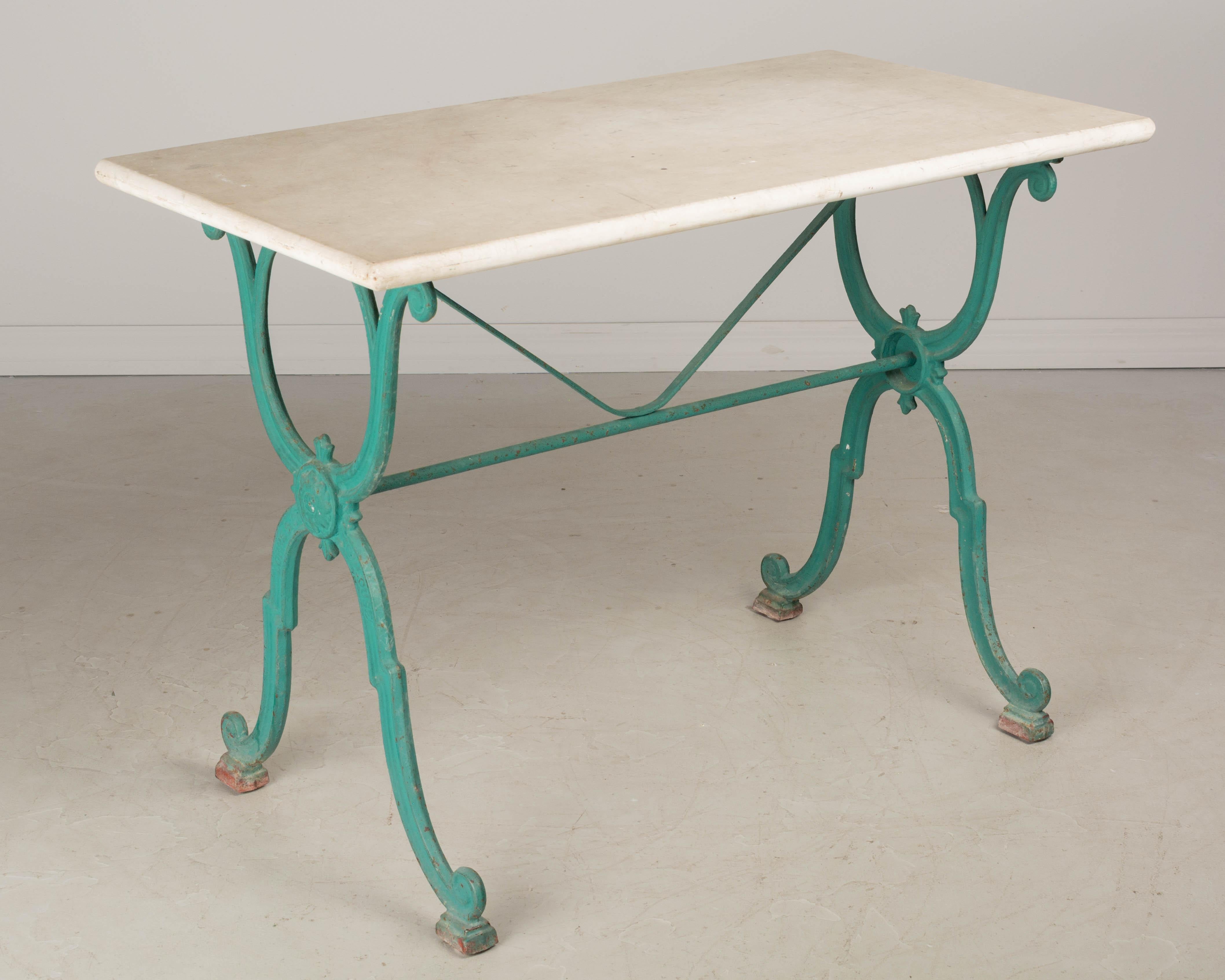 A 19th century French cast iron, marble top bistro table, or garden table, with marble top. The turquoise painted iron base is stamped with the foundry: Corné & Cie. Toulouse. Good quality, heavy casting with minor paint loss and rusting at feet.