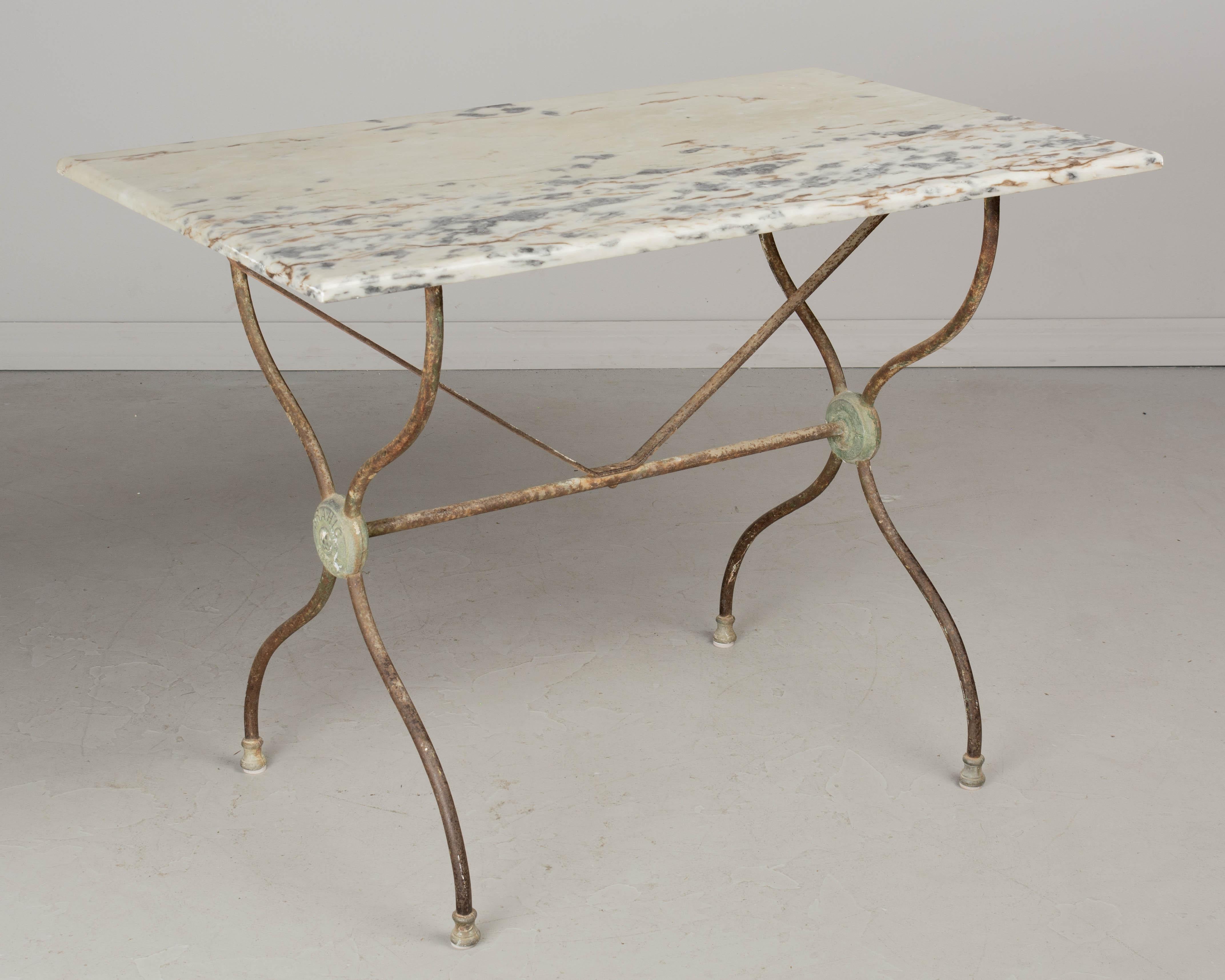 A 19th century French cast iron bistro table with rusty patina and verdigris medallions that read Brahic Nimes. Nice old marble top with interesting gray and brown veining. Circa 1880-1900. 
Dimensions: 39.5