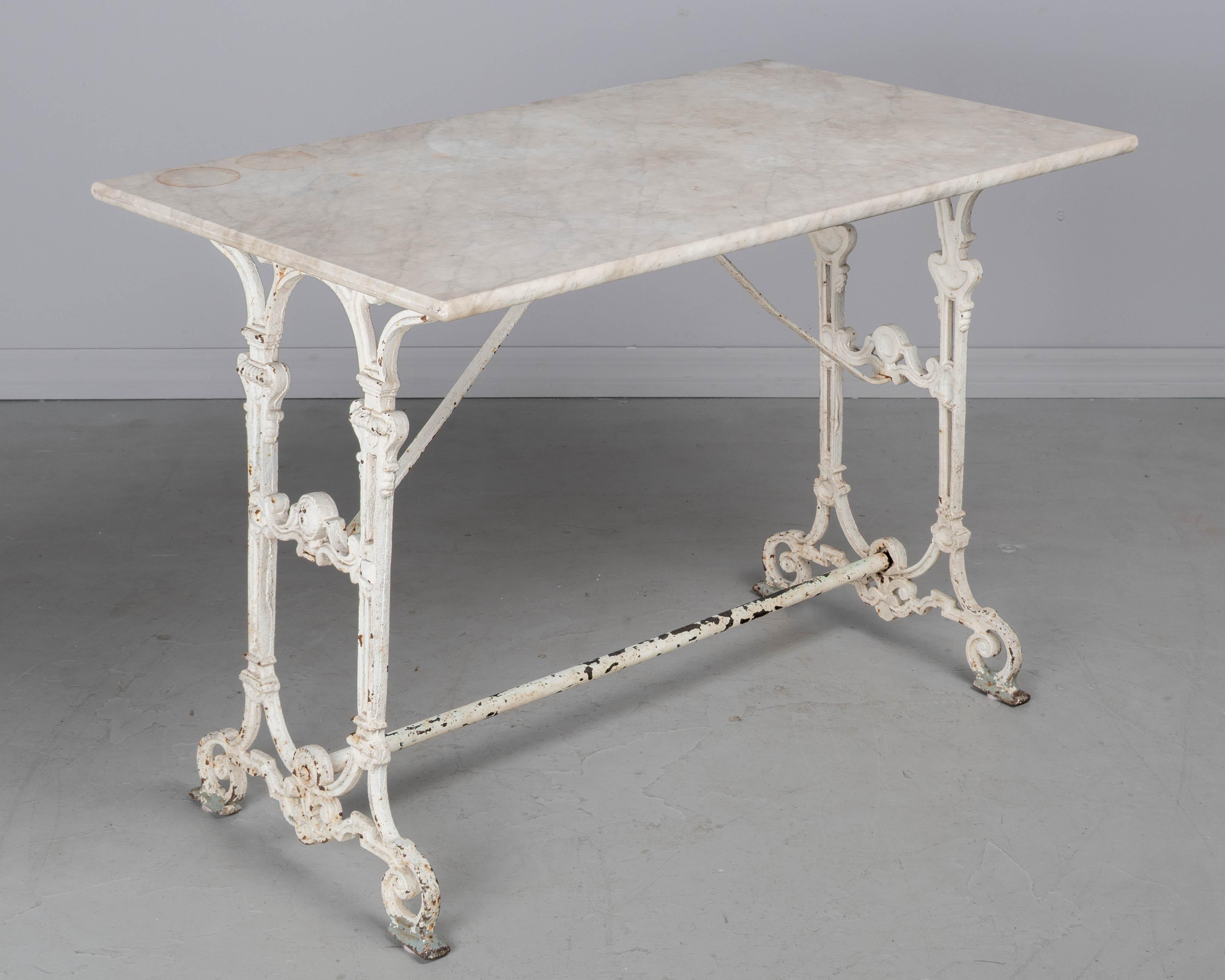 A 19th century French cast iron, marble top bistro table, or garden table, with white painted patina. Good quality, heavy casting with minor paint loss and rust. Original marble top with weathered patina and some rust stains. Great for indoor or