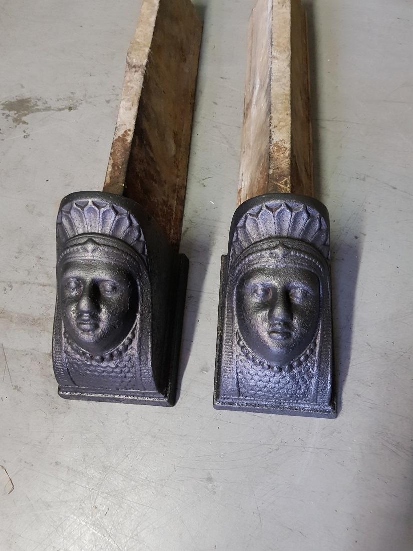 Old French cast iron neoclassical andirons with women's heads as decoration, both are in good but used condition. Originating from the 19th century.

The measurements are,
Depth 51 cm/ 20 inch.
Width 11 cm/ 4.3 inch.
Height 14 cm/ 5.5 inch.