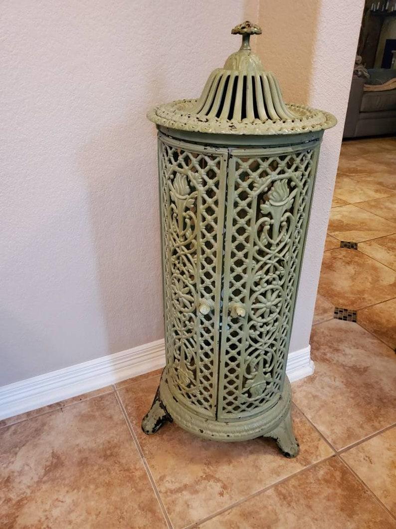 A late 19th century French cast iron parlor heating stove with beautiful patina. This antique stove features a tubular shaped body with two doors and a removable top with finial. The cast iron is finished in a pale green colored paint that's nicely