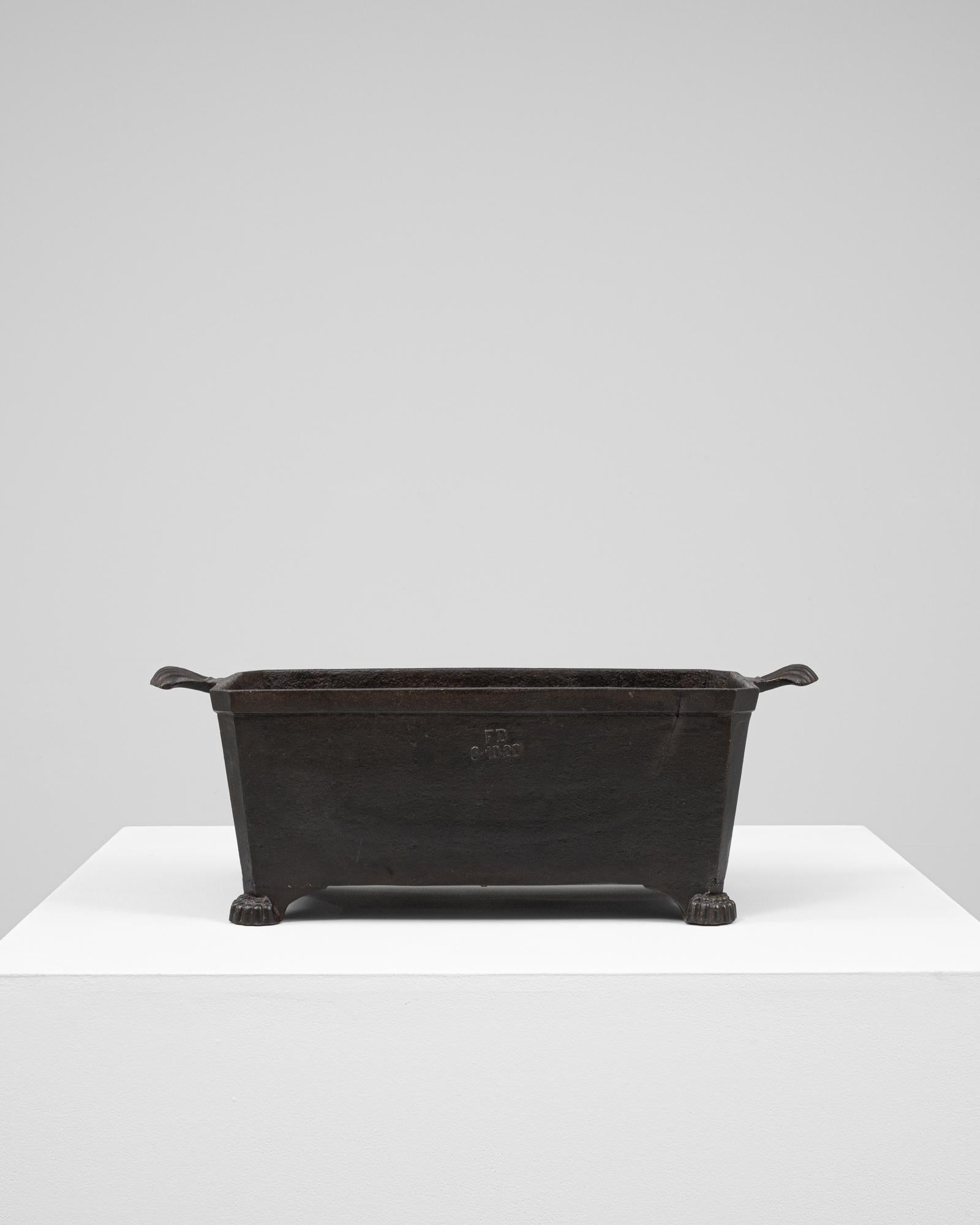 This 19th Century French cast iron planter is a refined example of utilitarian design imbued with classical detailing. Rectangular in form, the planter features gently flared sides, integrated side handles, and rests on four paw feet—each subtly