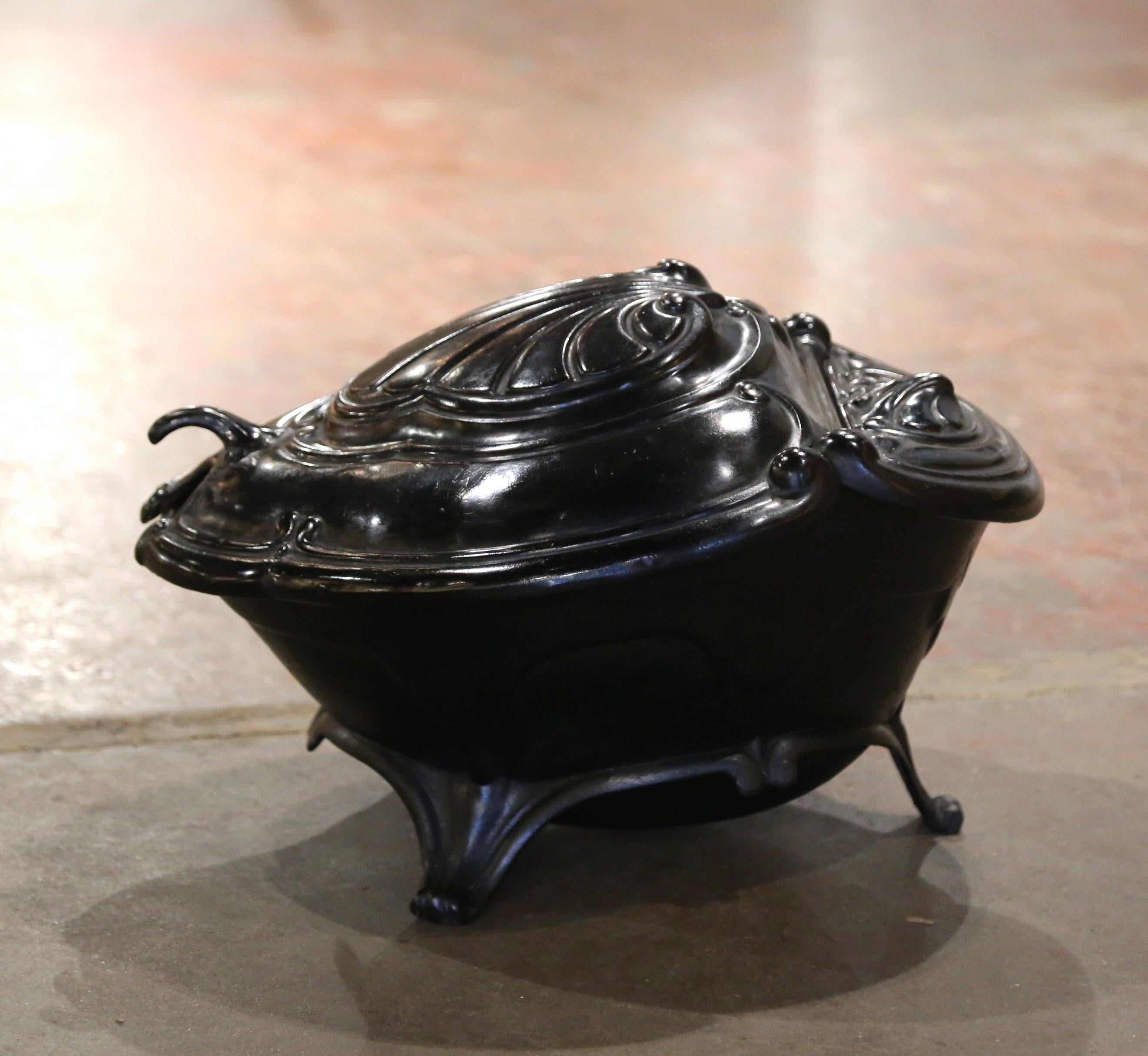This antique coal scuttle was created in France, circa 1870. Built of cast iron, and shaped as a shell with foliage repousse decor, the patinated bucket stands on escargot feet over a scalloped apron. The bucket features a hook form handle at the