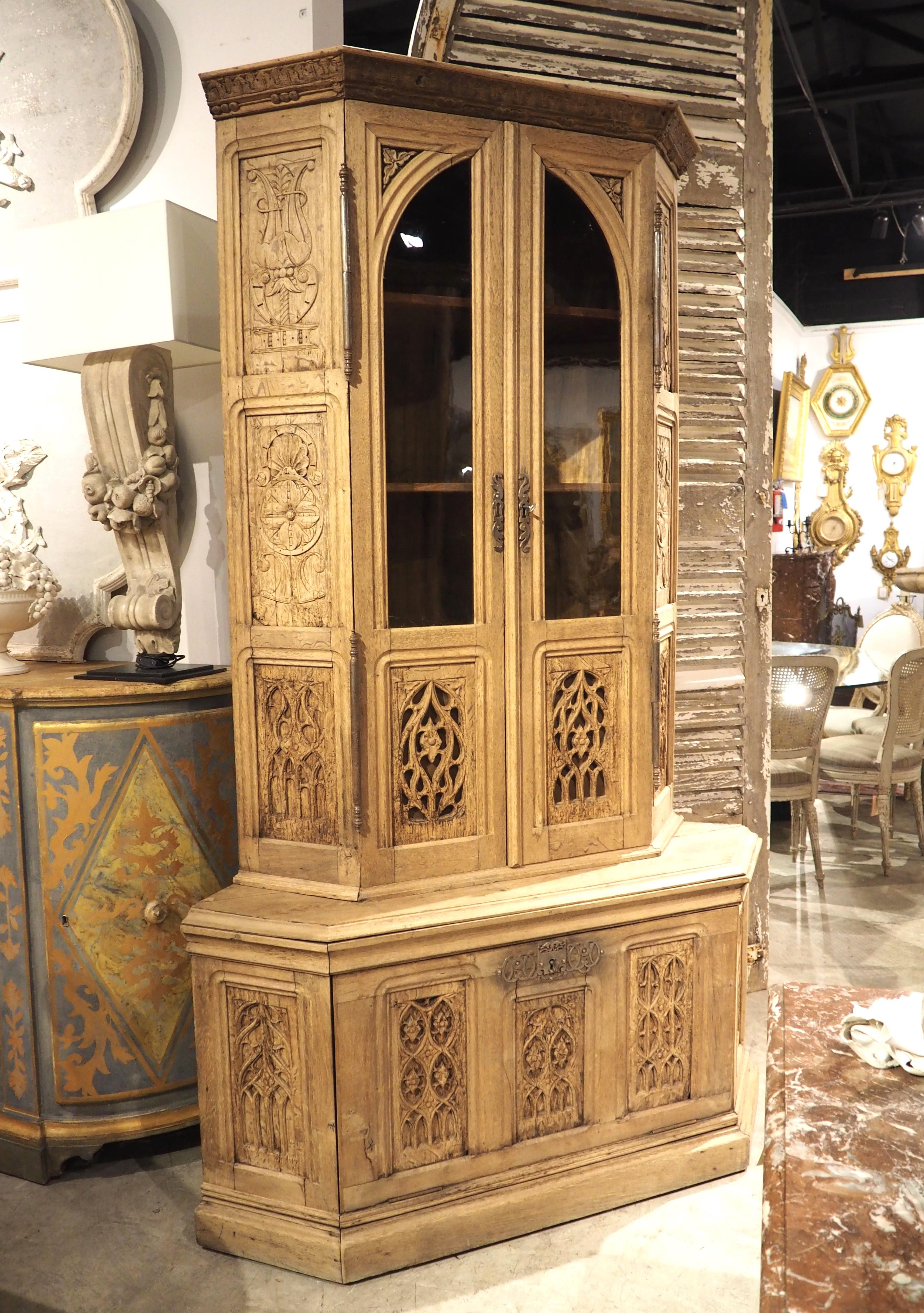 I pannelli a traforo di questa vetrinetta angolare in Oak sono stati intagliati a mano durante il periodo gotico. Un ebenista francese di grande talento ha incorporato gli intagli di recupero in questo mobile angolare a due corpi, che risale al 1870