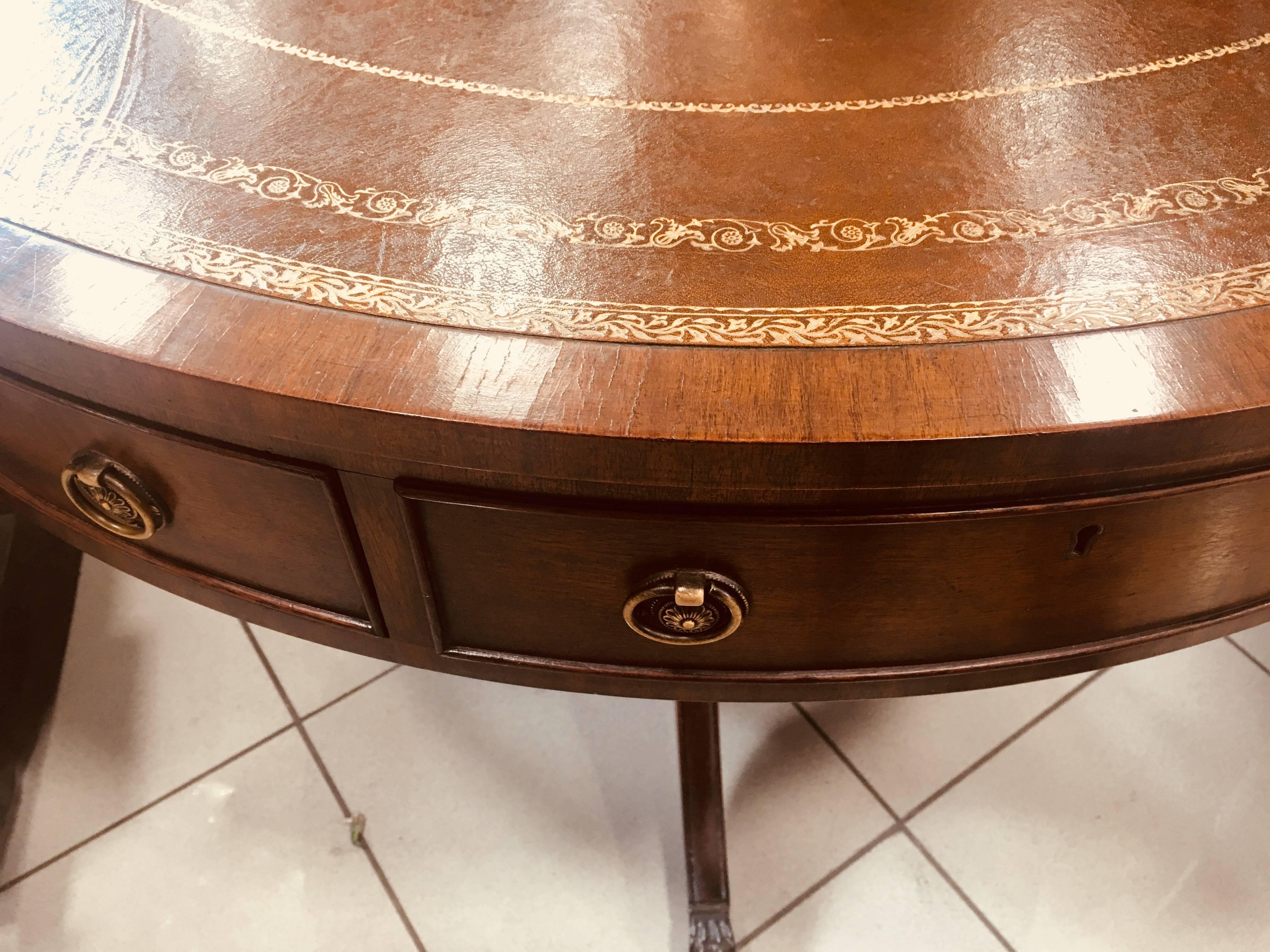 19th century antique French centre pedestal table in mahogany with aged brown leather top with gold ornaments. The apron has six drawers with round brass handles. There is a central shaped base with curved legs terminating in original brass cap