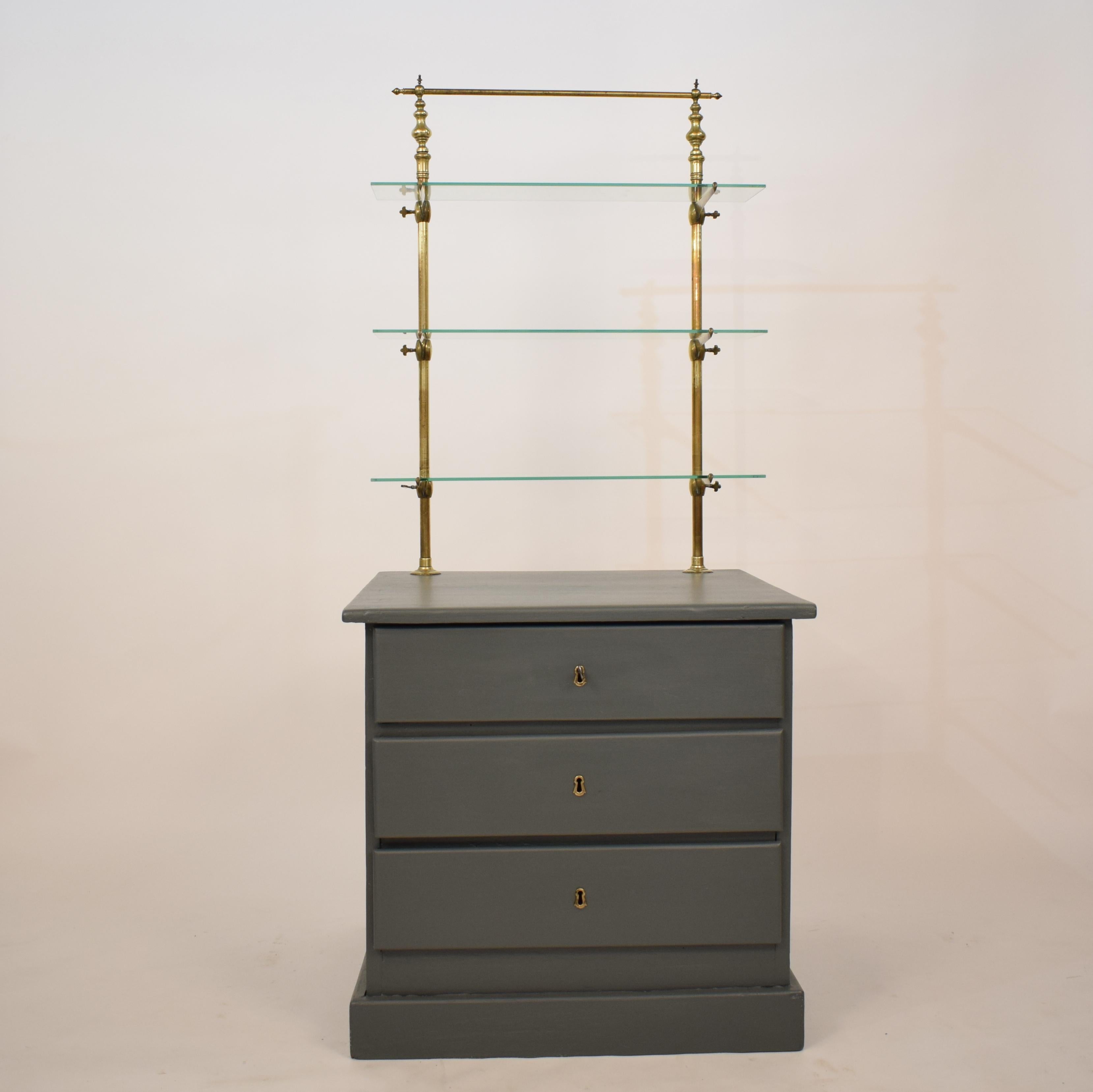 This beautiful 19th century French century grey shop counter has got three drawers and on top a brass shelf with three glass shelfs which is adjustable in height.
The chest is hand - repainted in a dark grey color. The 3 drawers are lockable.
There