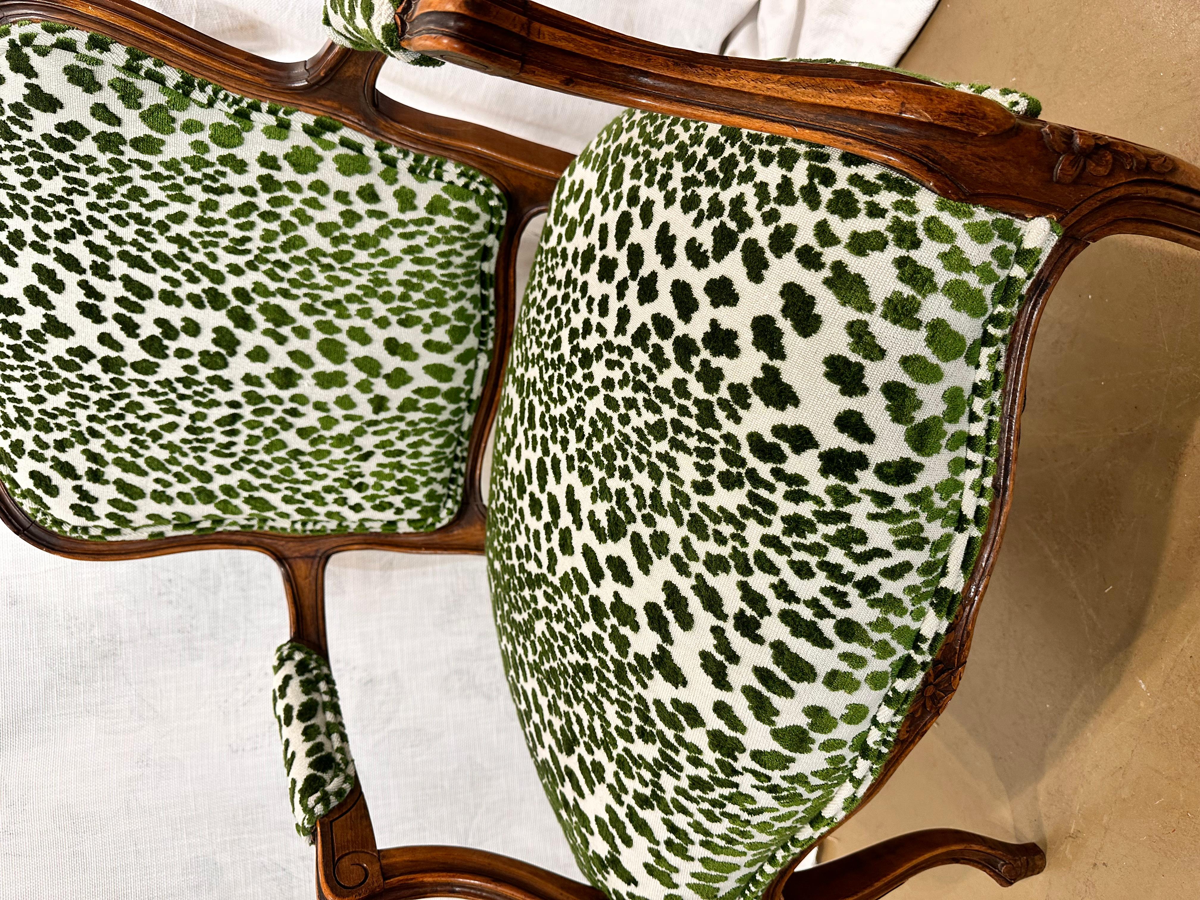 This is a beautiful, antique upholstered chair! It has been newly reupholstered in a vibrant green leopard print fabric that pairs wonderfully with the dark wood. The arms and legs have stunning hand carved designs that are immediately eye-catching.