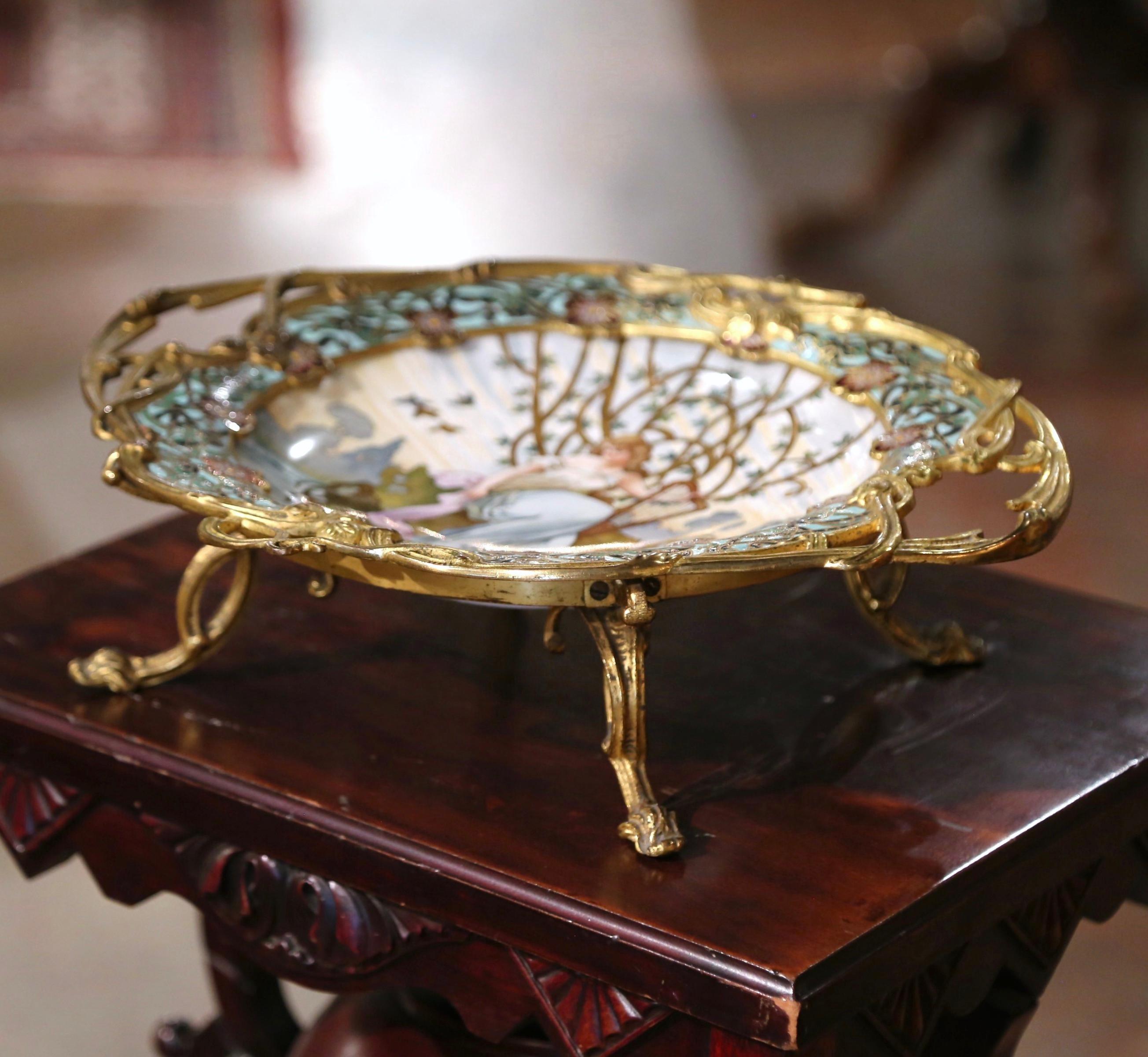 Decorate a dining table or a console with this elegant antique centerpiece. Crafted in France circa 1890, and signed Tisserand, the colorful tray stands on small curved feet over an oval porcelain plate decorated with a Champleve border with floral