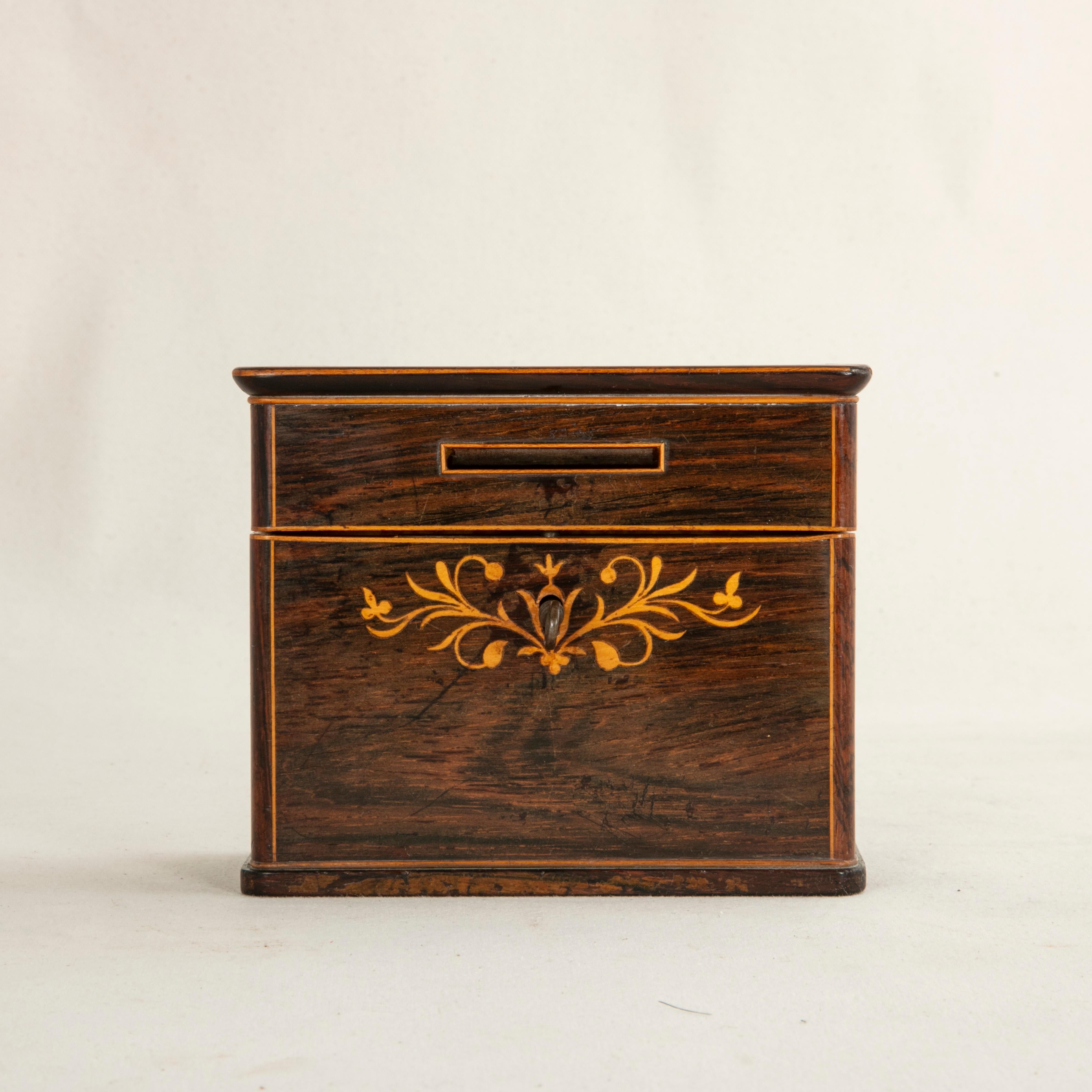 This early 19th century French Charles X period coin box is constructed of mahogany and features inlaid lemon wood borders. The lemon wood inlay on the lid reads Epargne, or Savings in English. Intricately scrolling inlaid leaves, also in lemon