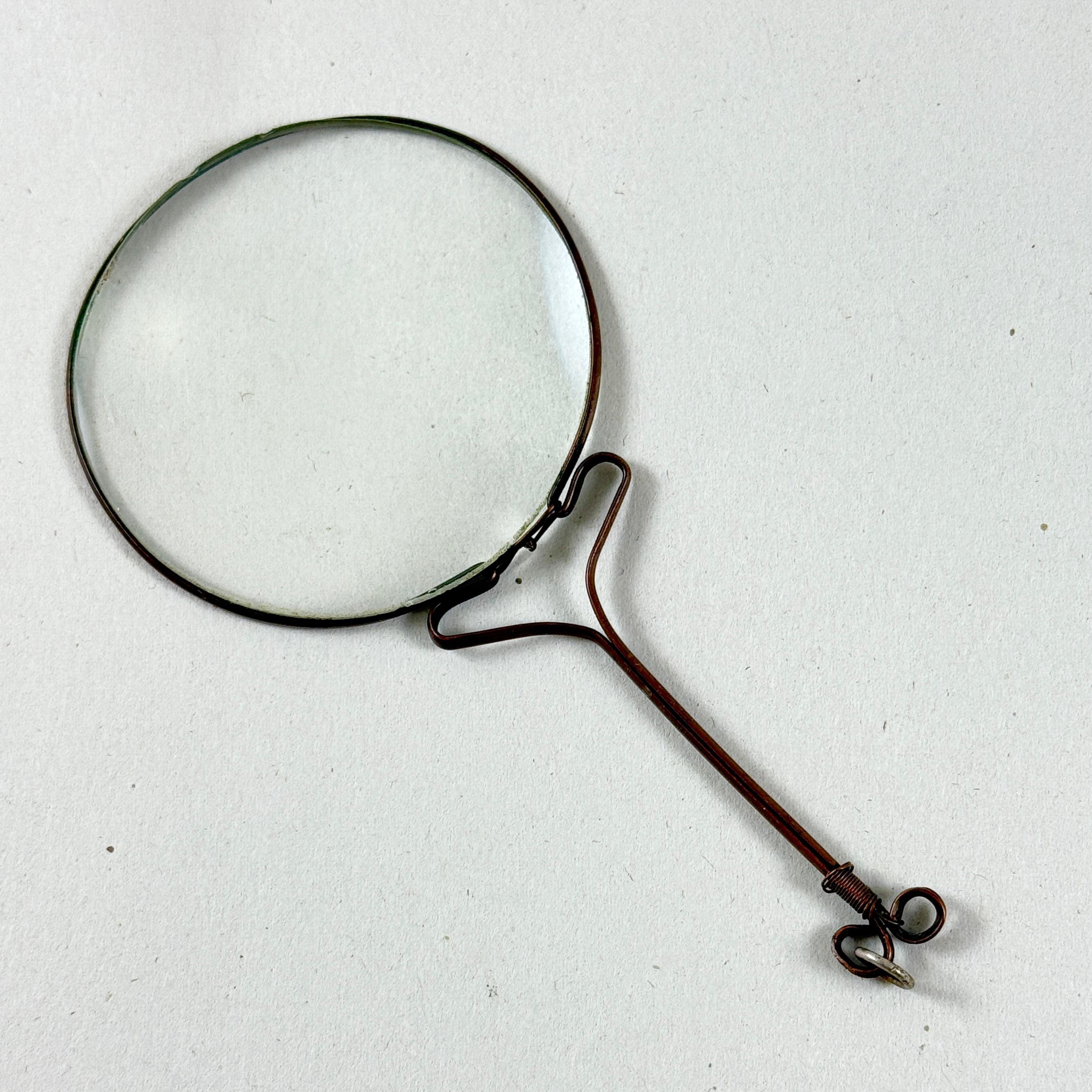 A handmade magnifying glass originally part of a chatelaine, dating to the early 19th Century, France.

A chatelaine is a decorative belt hook worn at the waist with a series of chains suspended from it. Each chain is mounted with useful household