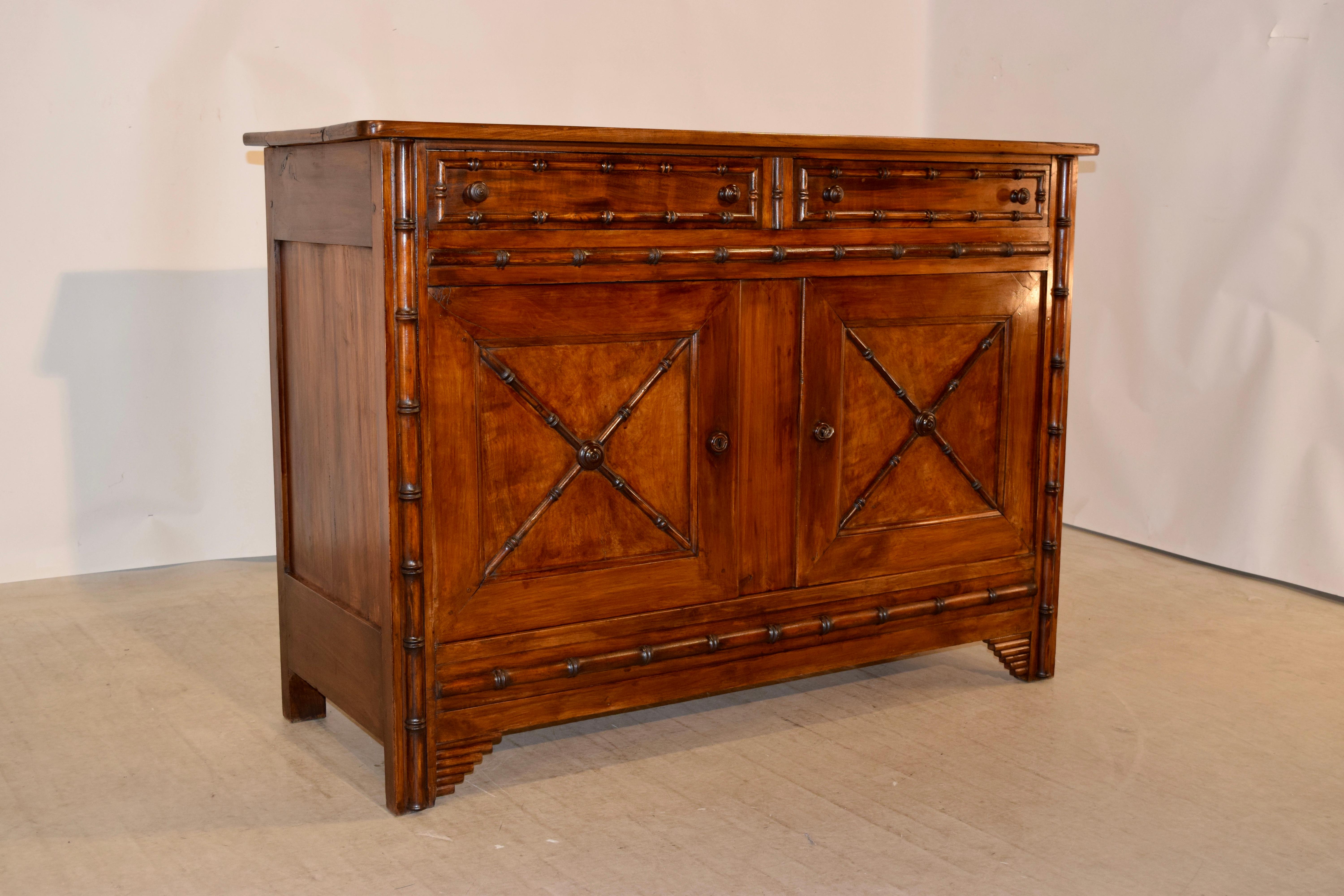 19th century cherry buffet from France with a plank top which has beautifully grained wood, following down to paneled sides and two drawers over two doors in the front. The drawer fronts, doors, and front of the case are decorated with hand-turned