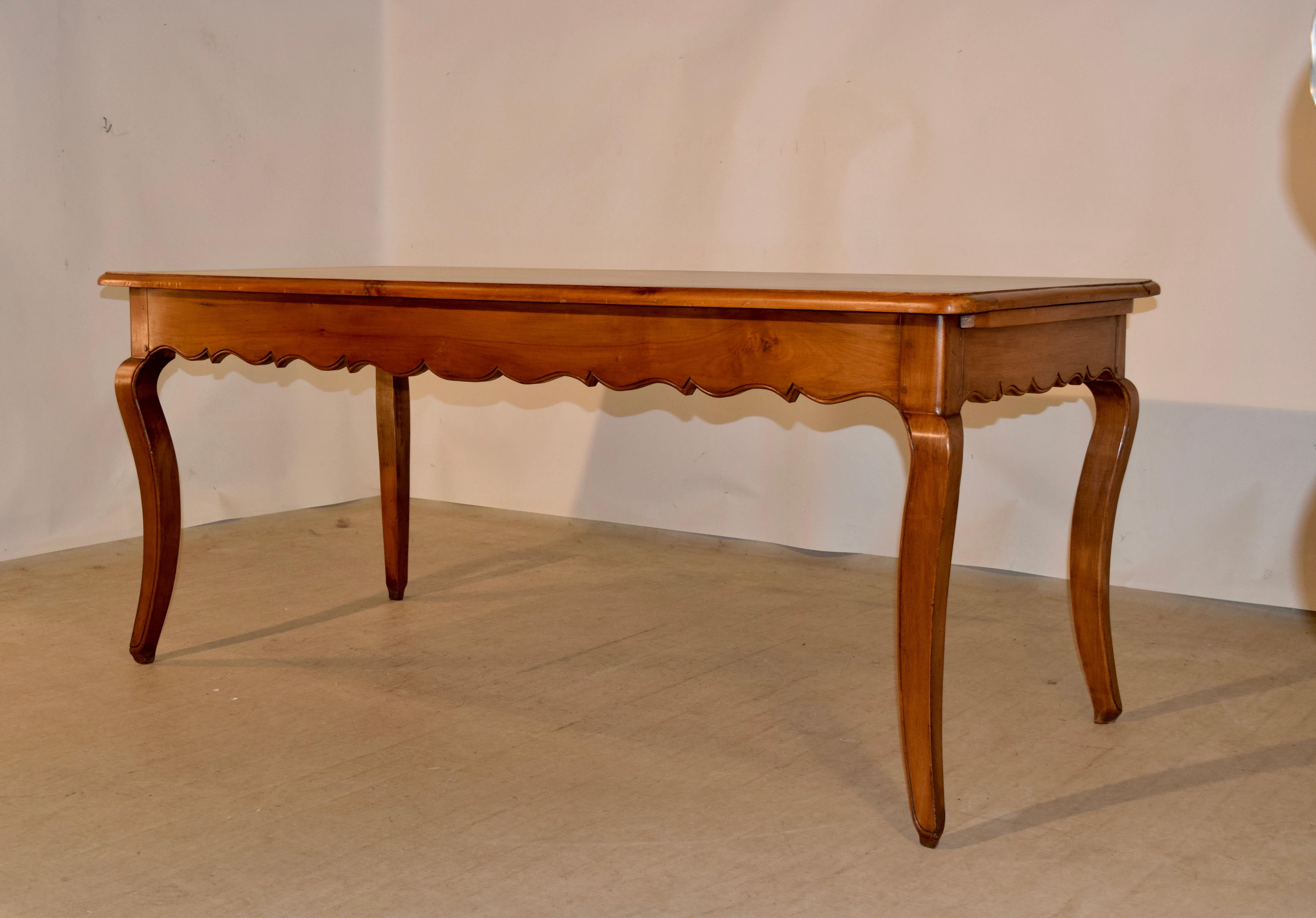 19th century farm table from France made from cherry with a banded top which has wonderful graining following down to a hand scalloped apron which contains a single drawer on one end and a bread board on the other. The table is supported on cabriole
