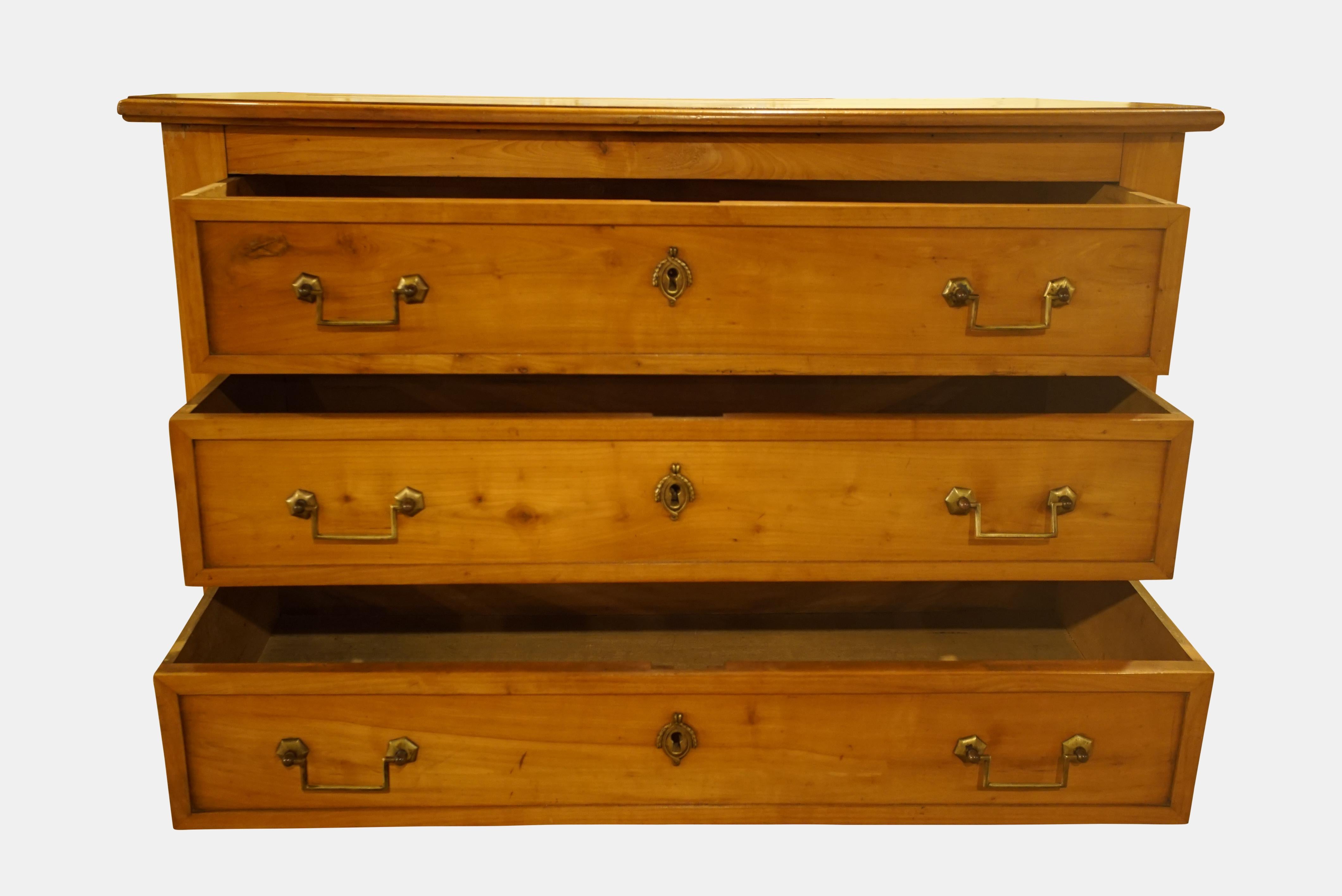 An unusual 19th century French cherry wood chest of drawers with brass handles and set on brass feet.