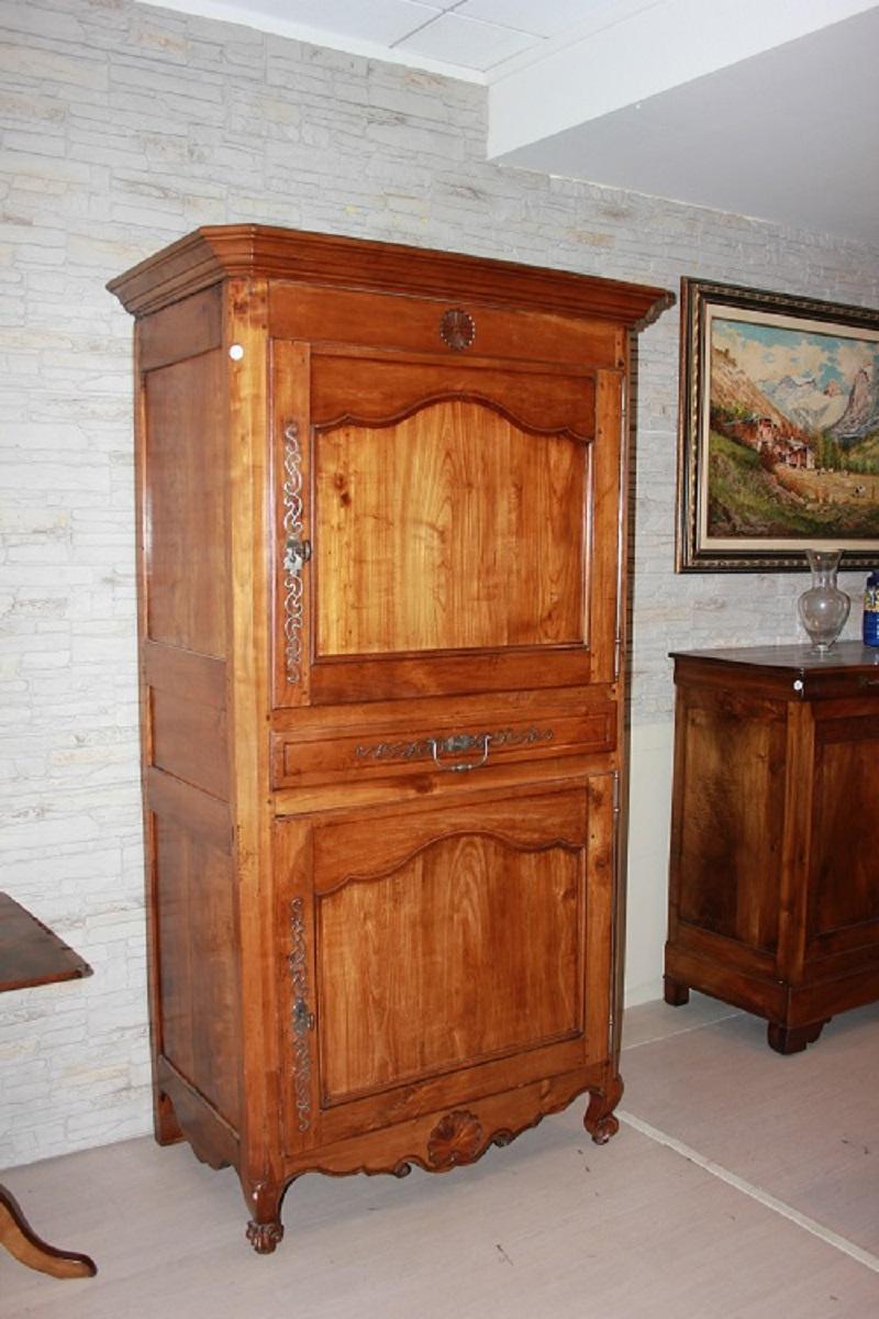 Französischer Schrank aus der ersten Hälfte des 19. Jahrhunderts, provenzalischer Stil, aus Kirschholz. Der obere Teil besteht aus einem Kranz und einer geschlossenen Tür, während der untere Teil eine Schublade und eine geschlossene Tür aufweist;