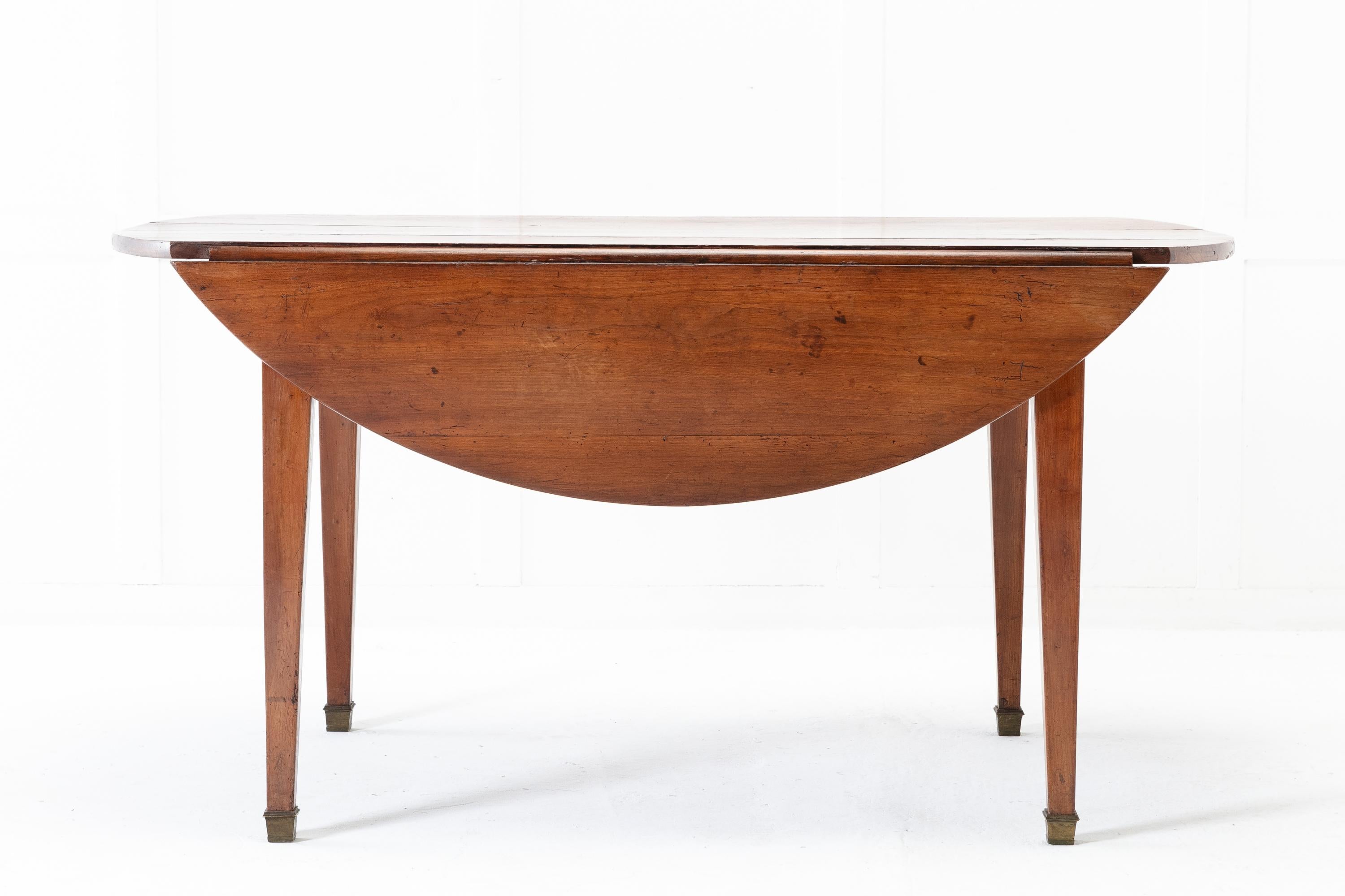 19th century French cherrywood dining table of oval shape when extended with drop leaves on each side. Expands with both drop leaves supported by pull-outs to create a table that can easily accommodate six people. Standing on sturdy, square tapering