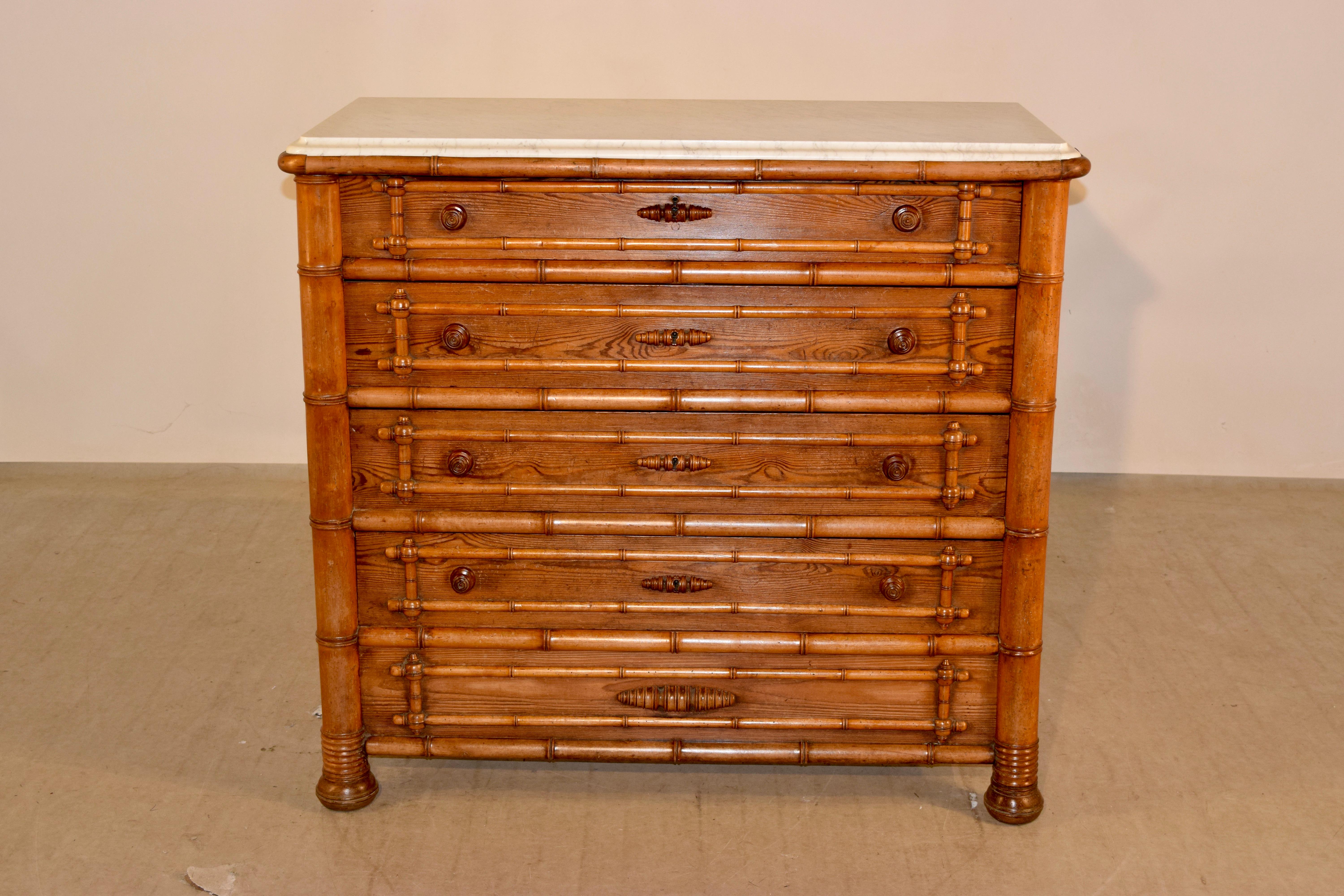 19th century faux bamboo pine and cherry chest of drawers from France. The top is made from Carrara marble and has a molded edge, which fits into the top faux bamboo hand turned molding of the piece. This follows down to four drawers in the front,